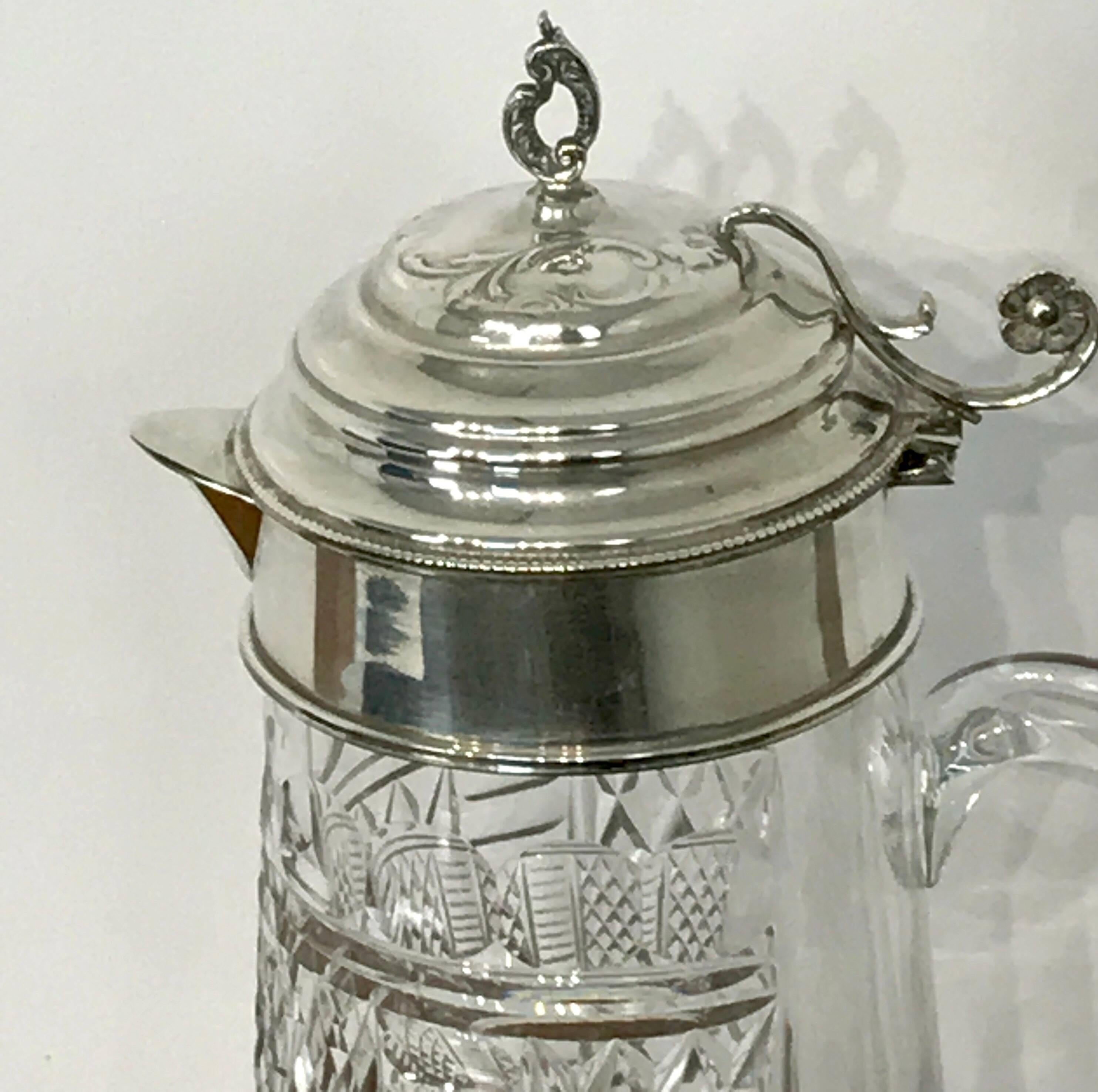 Large sterling mounted cut-glass claret jug, with hinged top, on a cylinder cut-glass diamond pattern handled jug. Measures: Standing 12.5