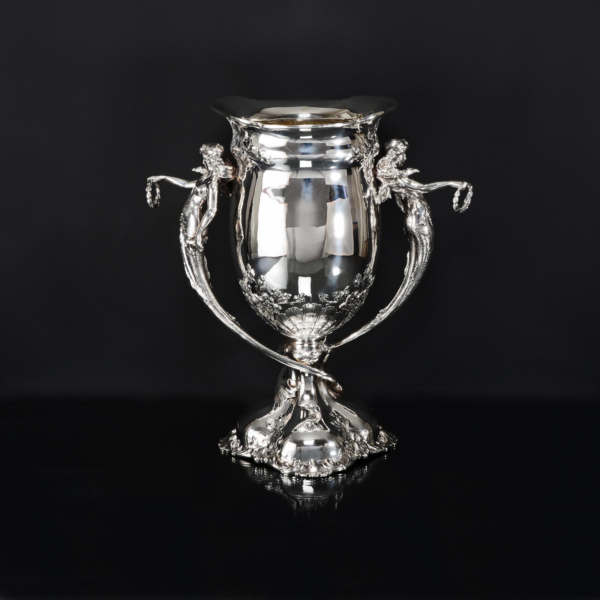 Large antique American silver vase made in the Art Nouveau style. The two swirling handles are beautifully modelled and cast in the the form of mermaids draped in seaweed and holding laurel wreaths in outstretched arms. The body and base of this