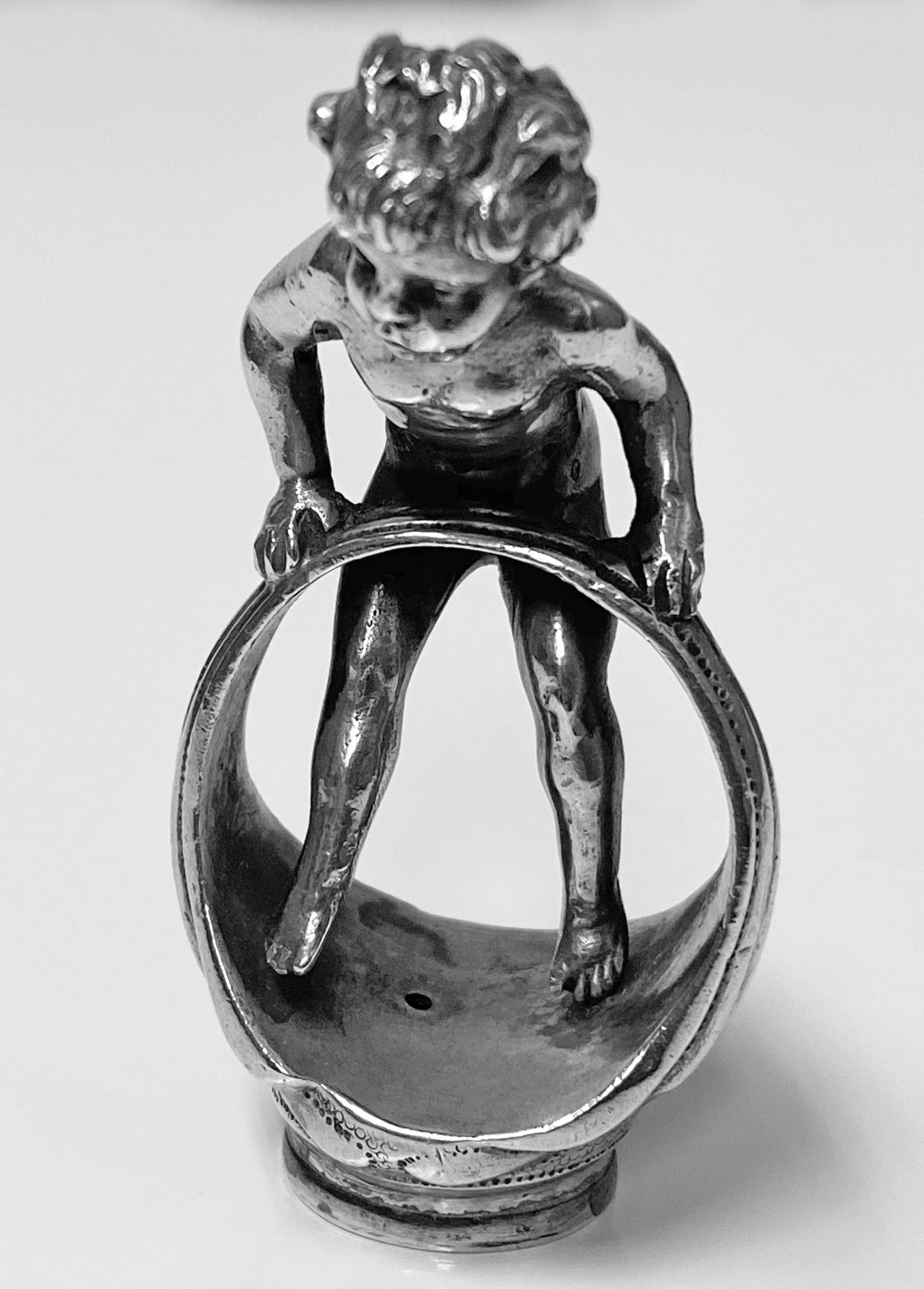 Large sterling silver desk seal with cherub or angelic figure in a finger ring engraved with crest of a cat at the base. Unusual nude figure balancing on the ring. The back of leg with import marks for Chester, 1912. Condition: Very good. Measures: