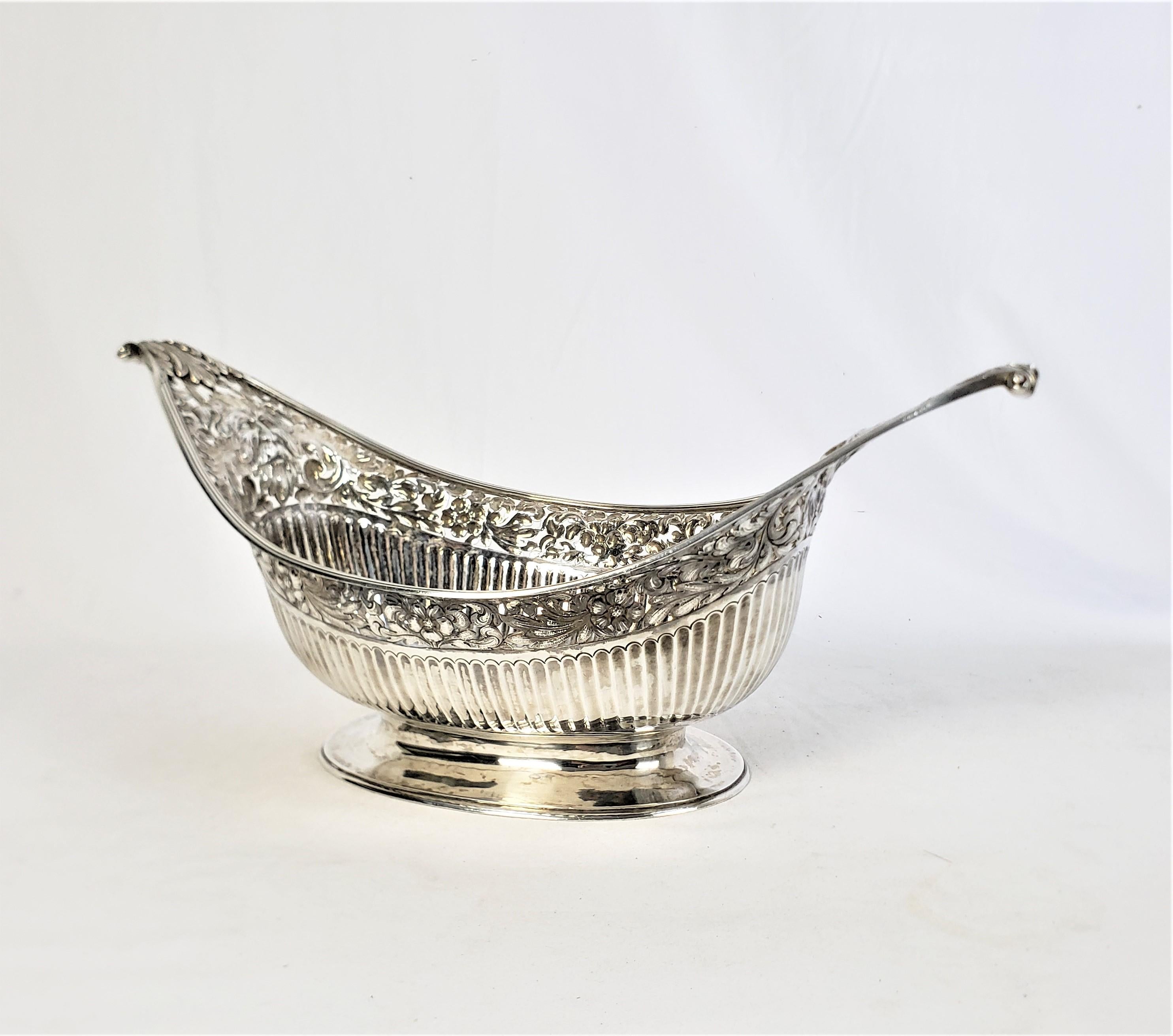 This large and substantial centerpiece basket was made by Timothy Renou of England in 1802 and done in the period Georgian style. The basket is composed of sterling silver and is eliptical in shade with high sweeping handles and ribbed sides. The