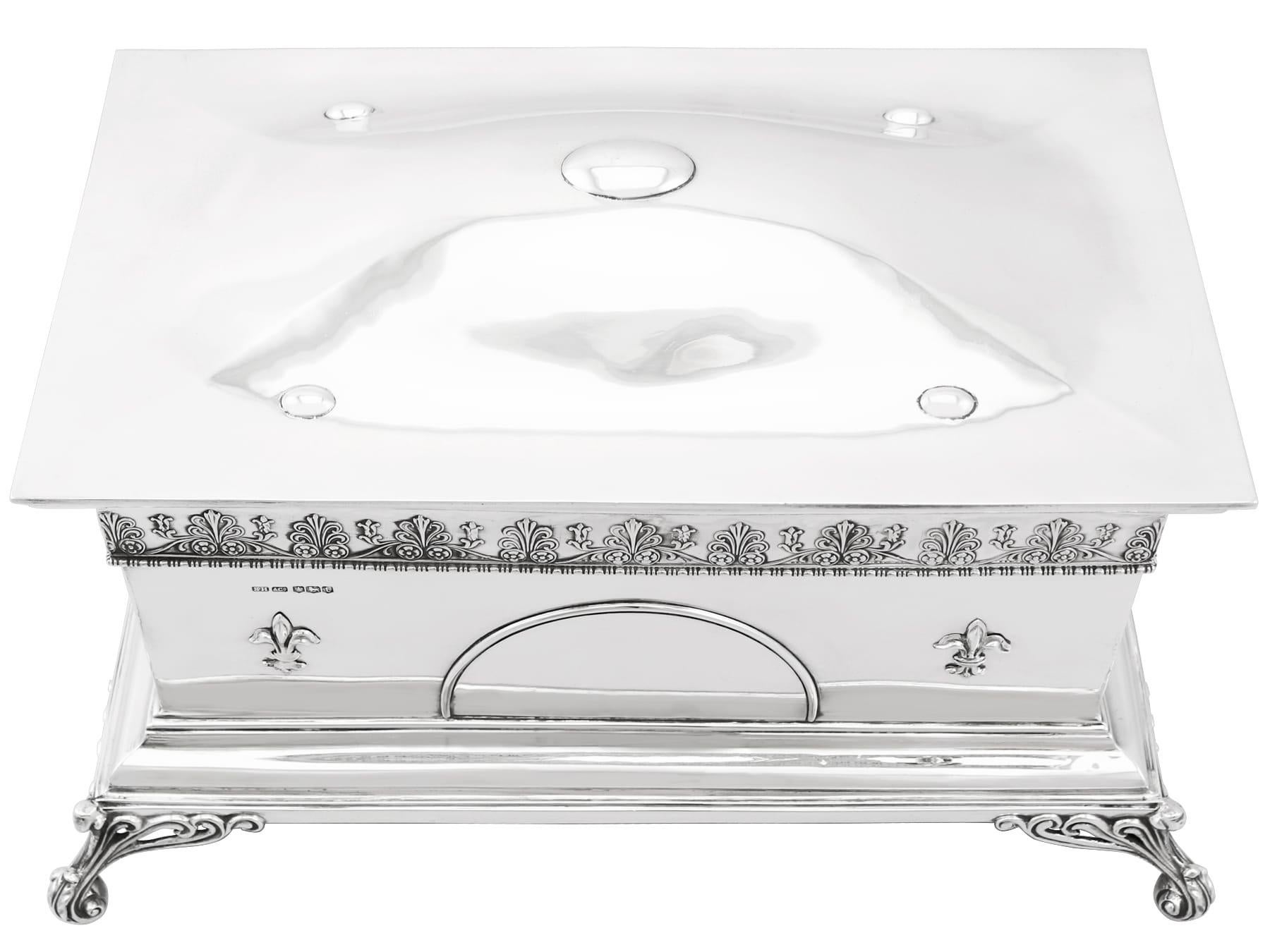 This magnificent antique jewellery casket in sterling silver has a rectangular form onto four bracket style feet.

The anterior surface of this antique Edward VIII jewelry casket is embellished with a semi-circular vacant cartouche flanked with