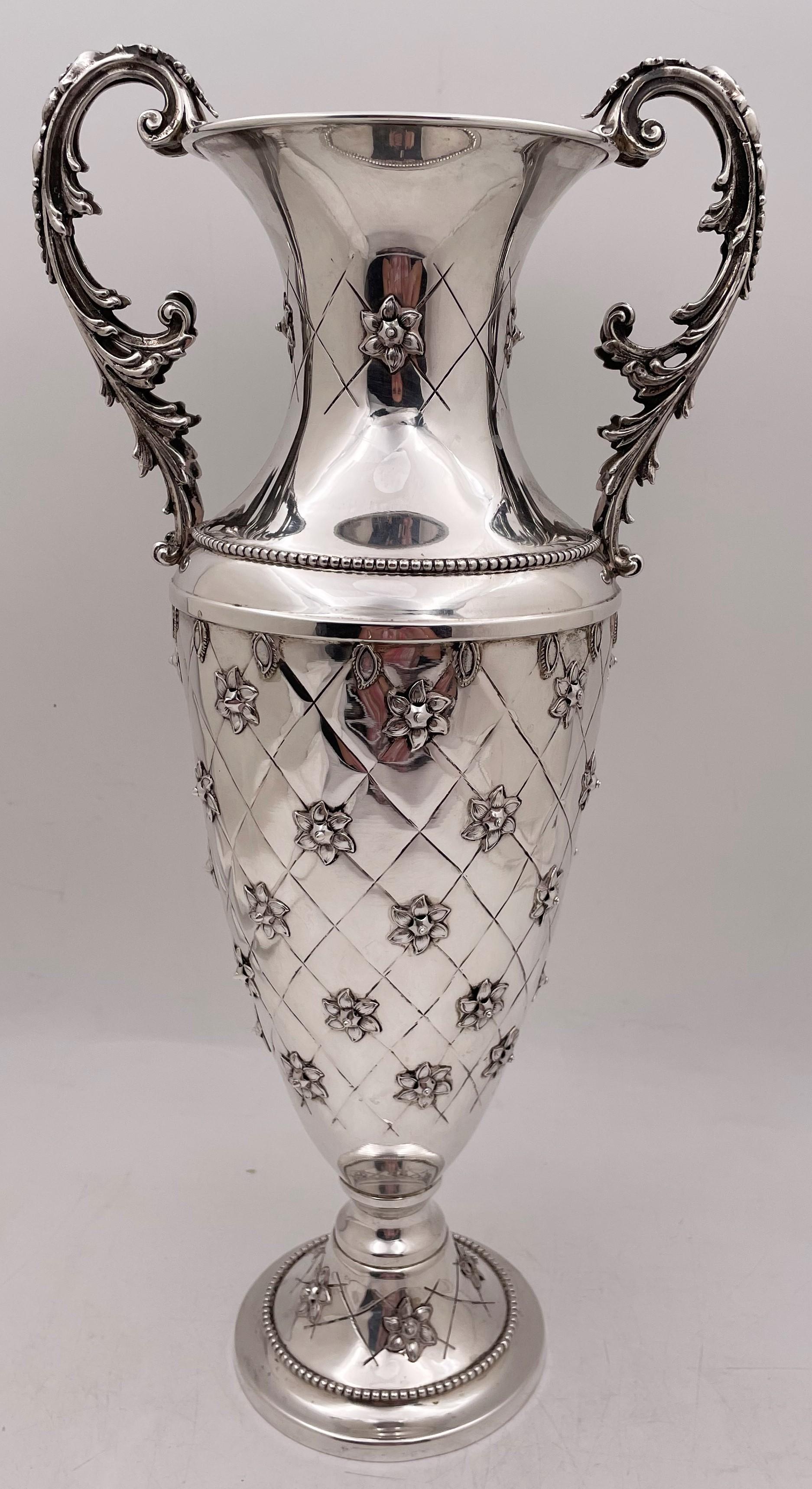 Sterling silver vase from the 20th century in a style reminiscent of Buccellati, with beaded motifs, applied floral motifs, and an elegant, geometric design, measuring 17 3/8'' in height by 8 1/2'' from handle to handle (4 7/8'' in diameter at the