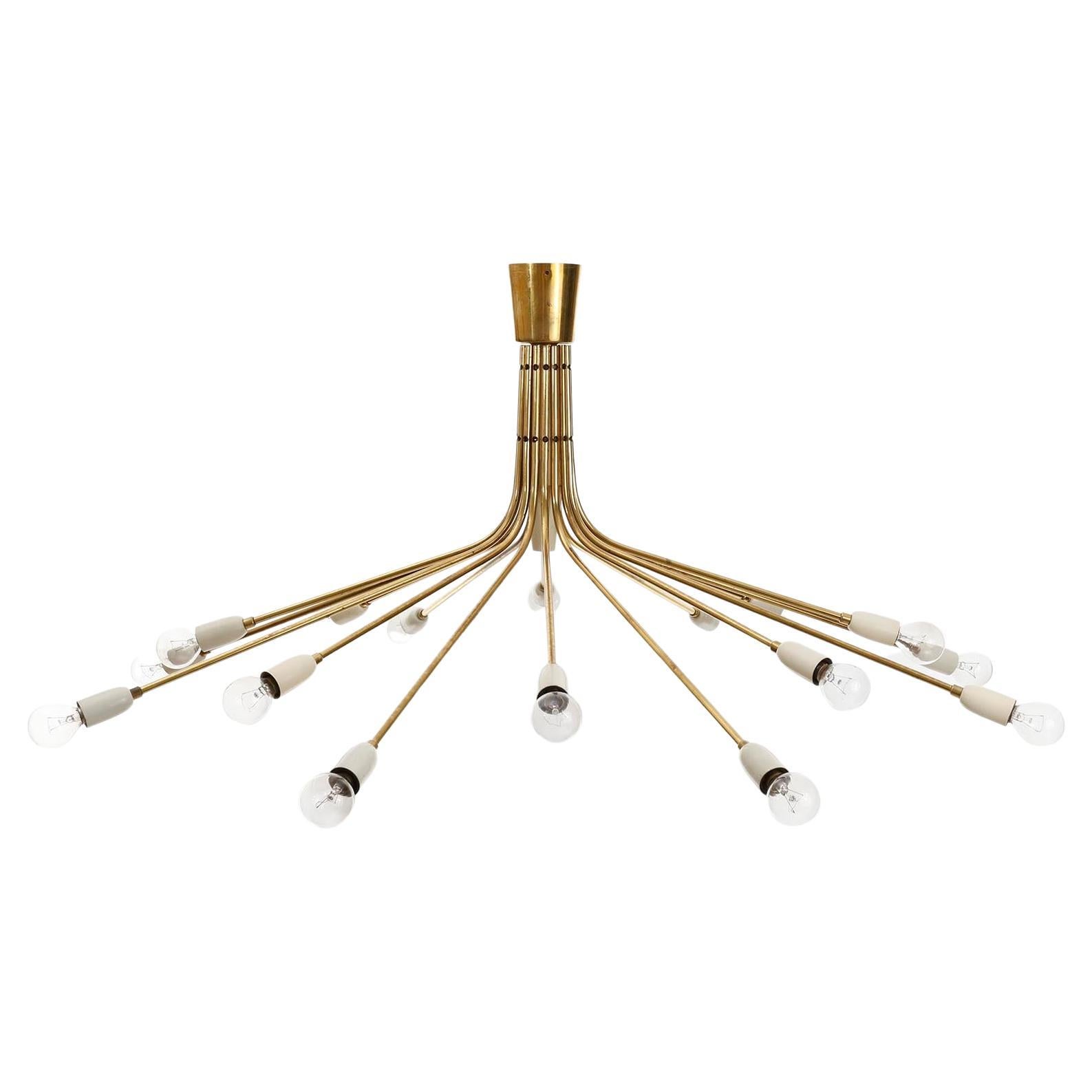 An Italian 16-arm flush mount ceiling fixture by Stilnovo, manufactured in Midcentury. A solid polished brass frame in warm aged tone with white lacquered fittings with nice patina on brass. This impressive chandelier holds 16 small base screw base