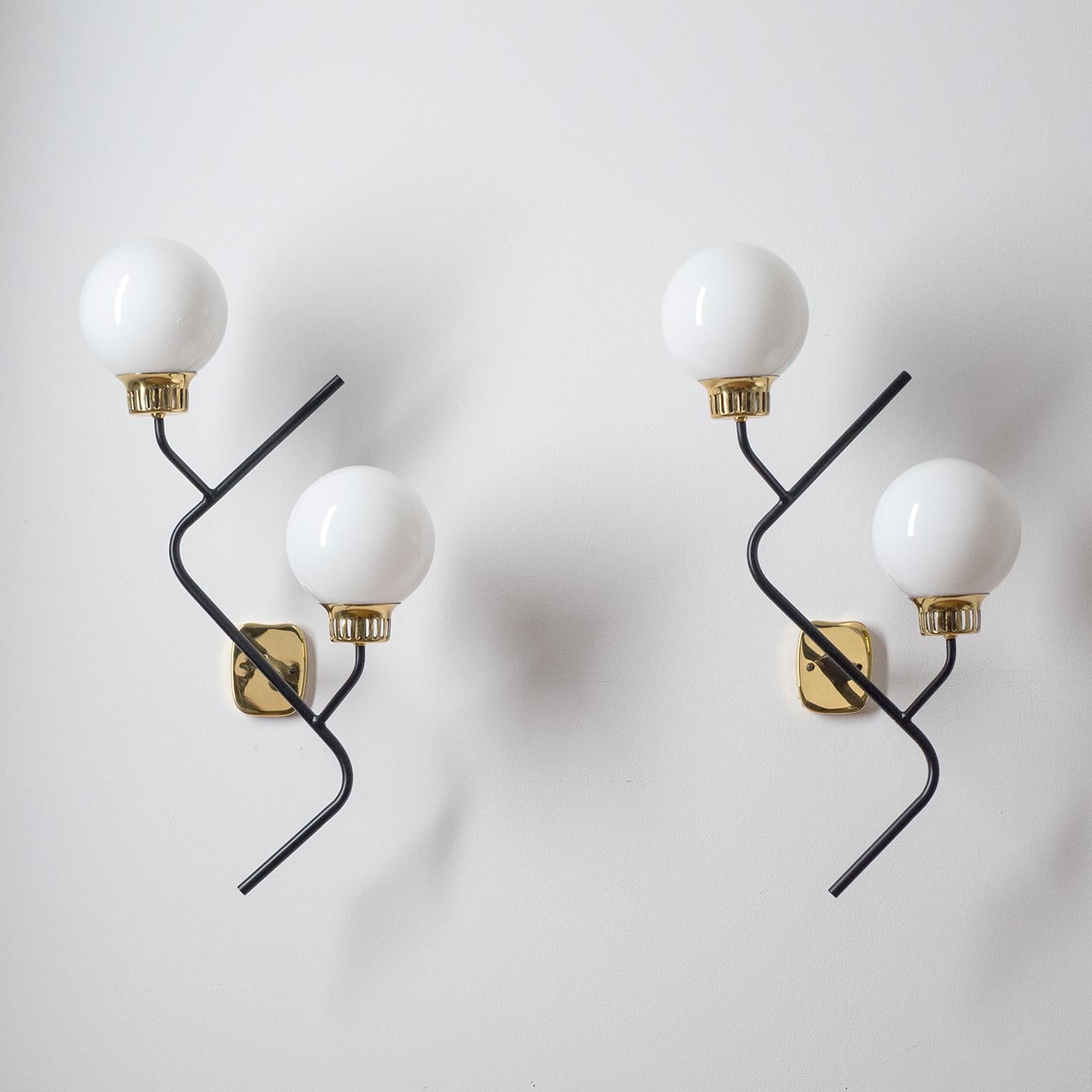 Exceptional pair of 1950s Stilnovo wall lights, dubbed 'Zig-Zag'. Lovely modernist rendition and design with black lacquered steel structure with brass socket covers and white cased glass diffusers. Very good restored condition with two brass and