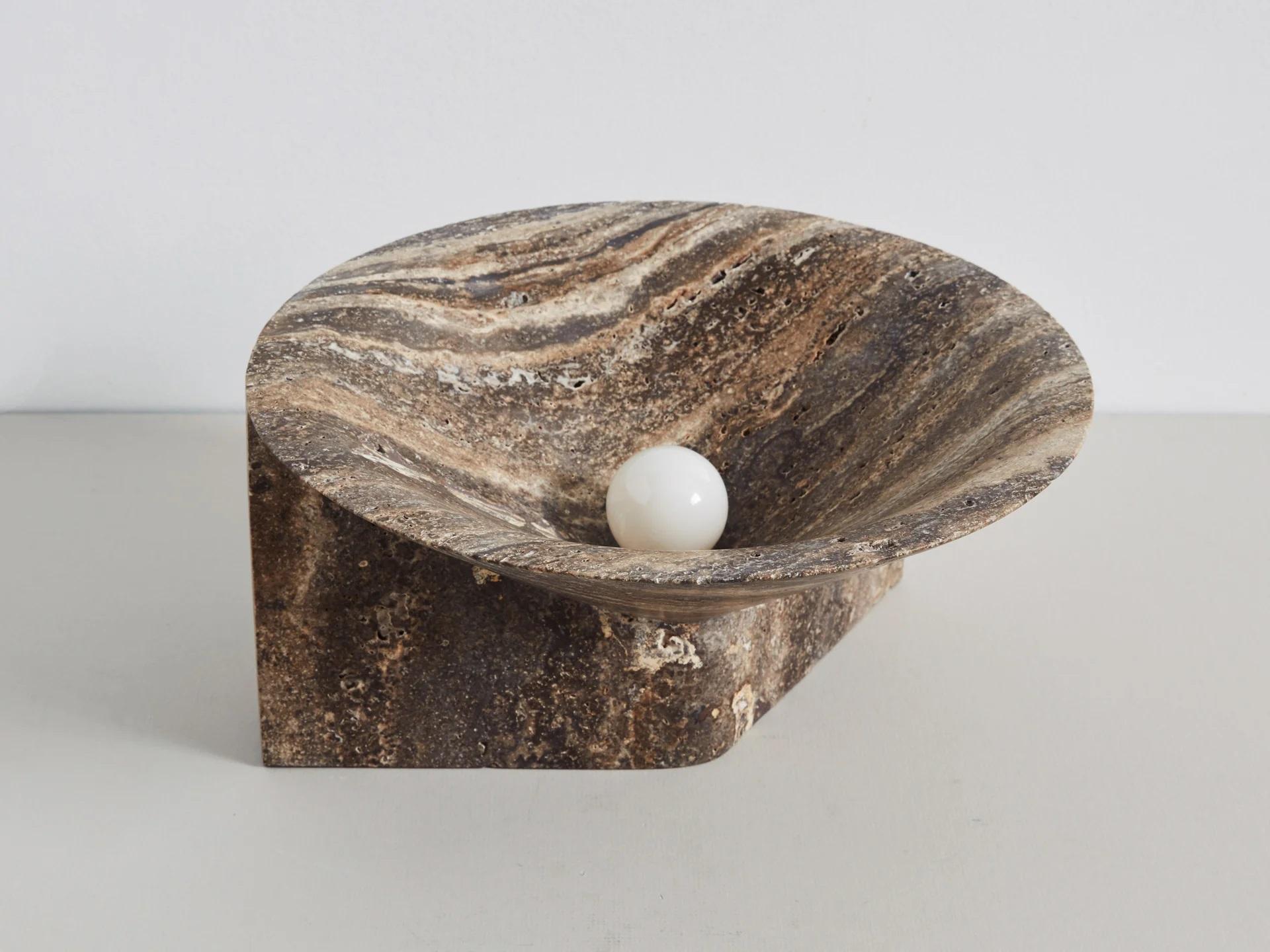 Large Stone Uplight by Henry Wilson
Dimensions: W 30 x D 30 x H 15 cm
Materials: Black travertine.

Also available in white alabaster.

This free-standing sculptural form, carved from a single block of stone in Porto, Portugal, emits a soft