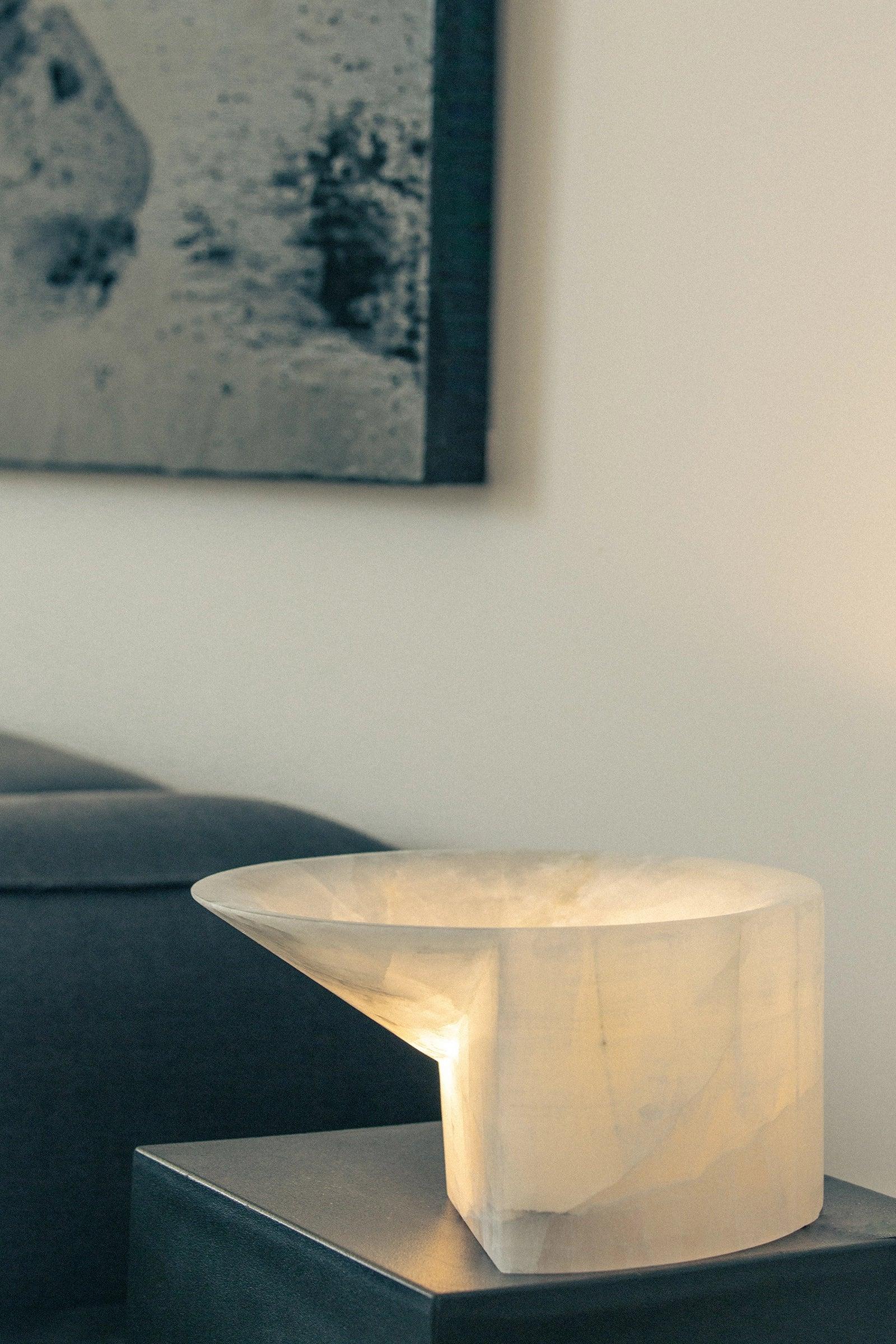 Large Stone Uplight by Henry Wilson
Dimensions: W 30 x D 30 x H 15 cm
Materials: White alabaster.

Also available in black travertine.

This free-standing sculptural form, carved from a single block of stone in Porto, Portugal, emits a soft