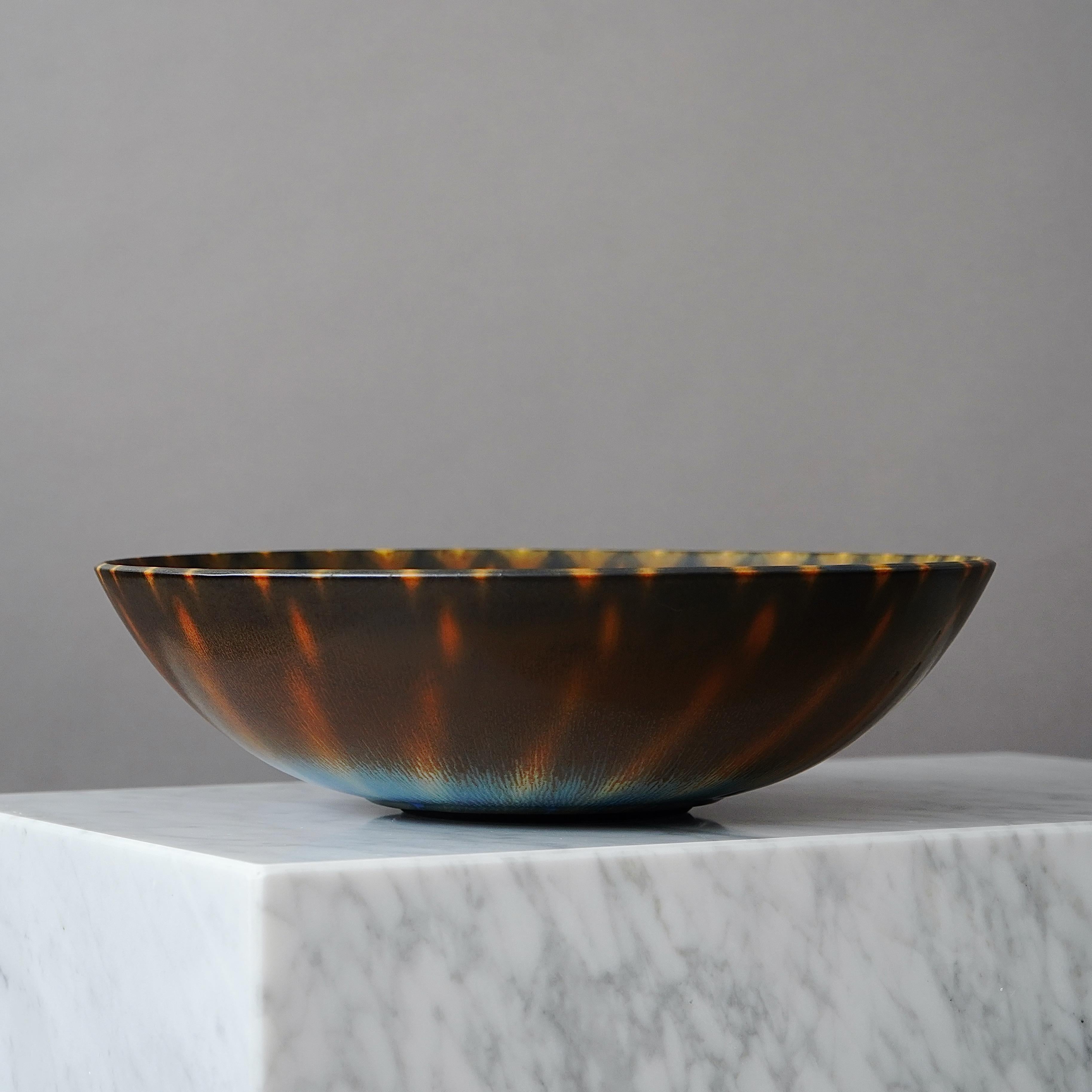 Un hermoso cuenco de gres con un sorprendente glaseado de pelo de liebre.
Realizado por el maestro lanzador Berndt Friberg, en el estudio del artista en Gustavsberg, Suecia, 1962.

Gran condición. 
Firma incisa 