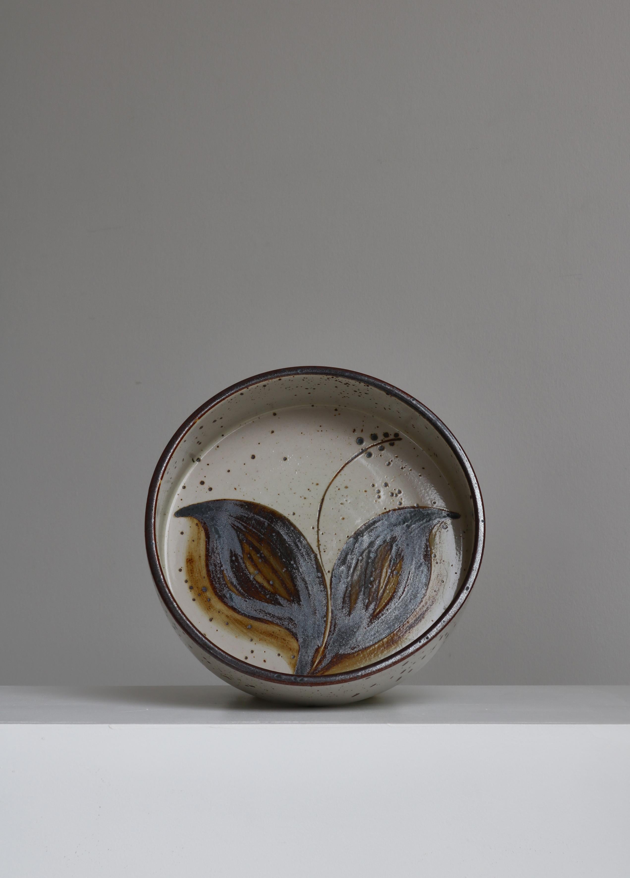 Large beautiful stoneware bowl handmade at Søholm Stoneware, Denmark in the 1970s. The bowl is hand decorated with a Japanese inspired floral motif depicting a stylized 
