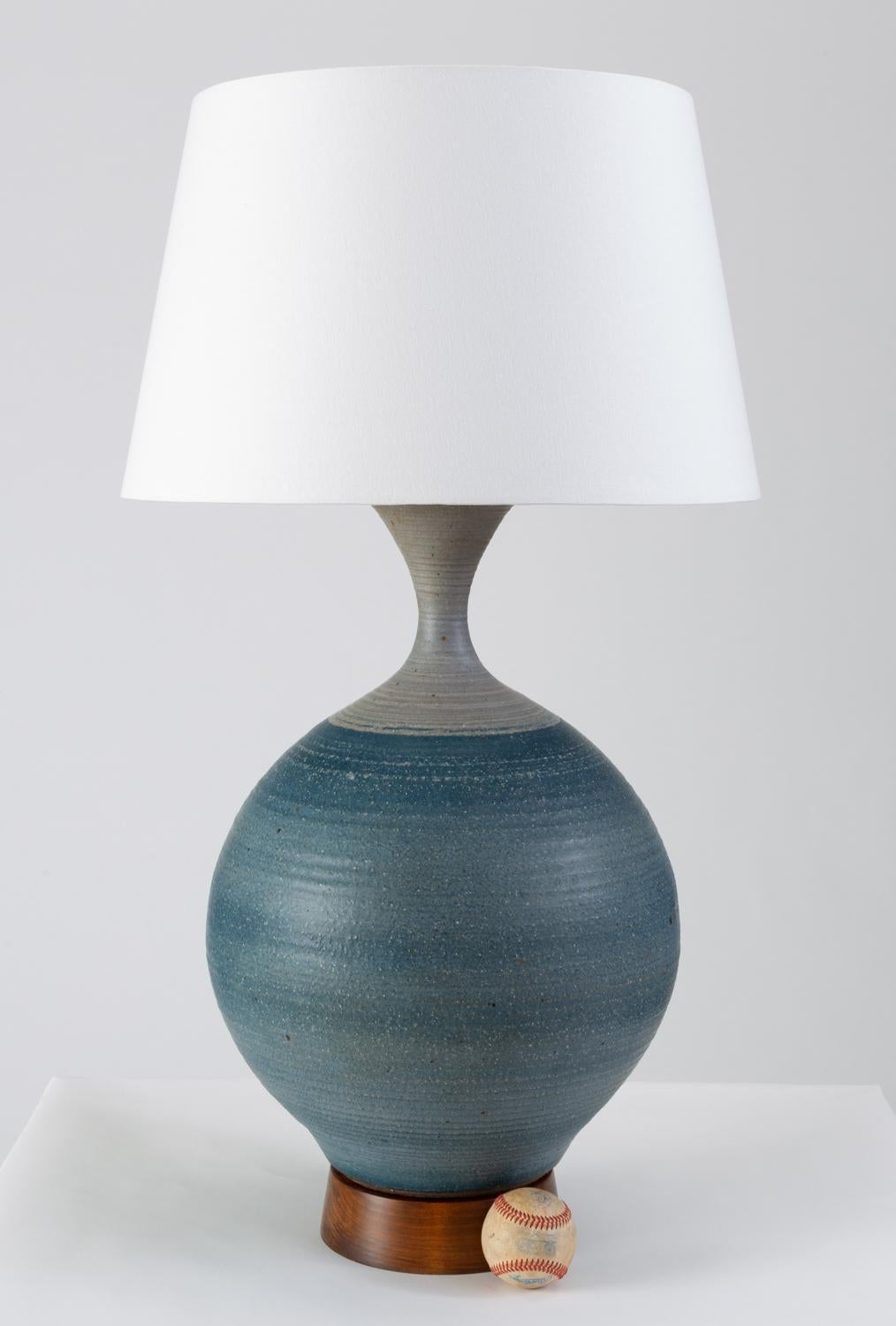 A large stoneware lamp by California ceramicist Bob Kinzie for his company, Affiliated Craftsmen with a curved body and wooden plinth base. The wheel-thrown ceramic body of the lamp is slightly textured and has a color-blocked glaze pattern in cyan