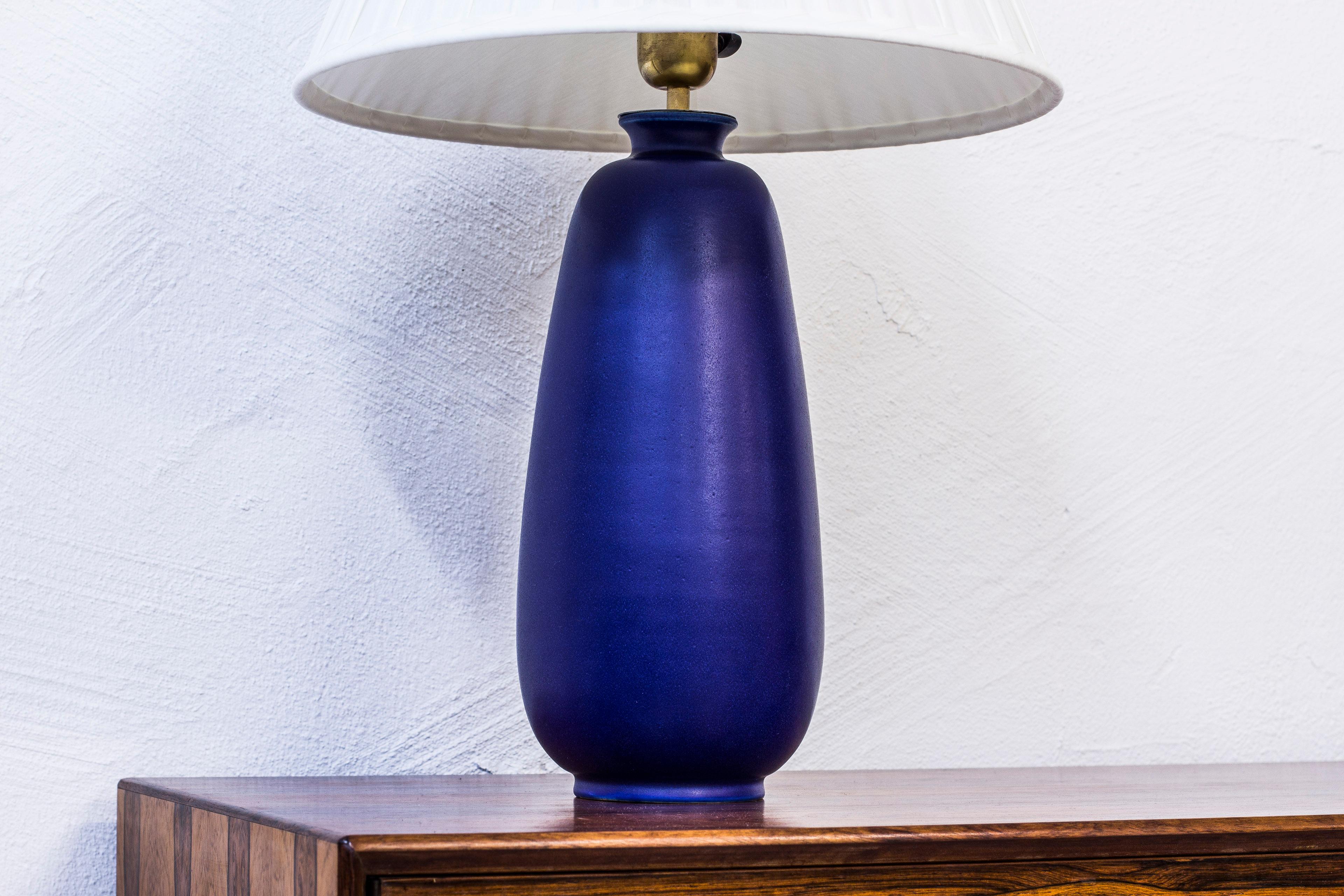 Unusually large table lamp designed and made by Erich & Ingrid Triller at their ceramic workshop Tobo, Sweden. Hand thrown stoneware with blue glaze. New lampshade hand-sewn in chintz fabric. Light switch on lighting fixture in working order.