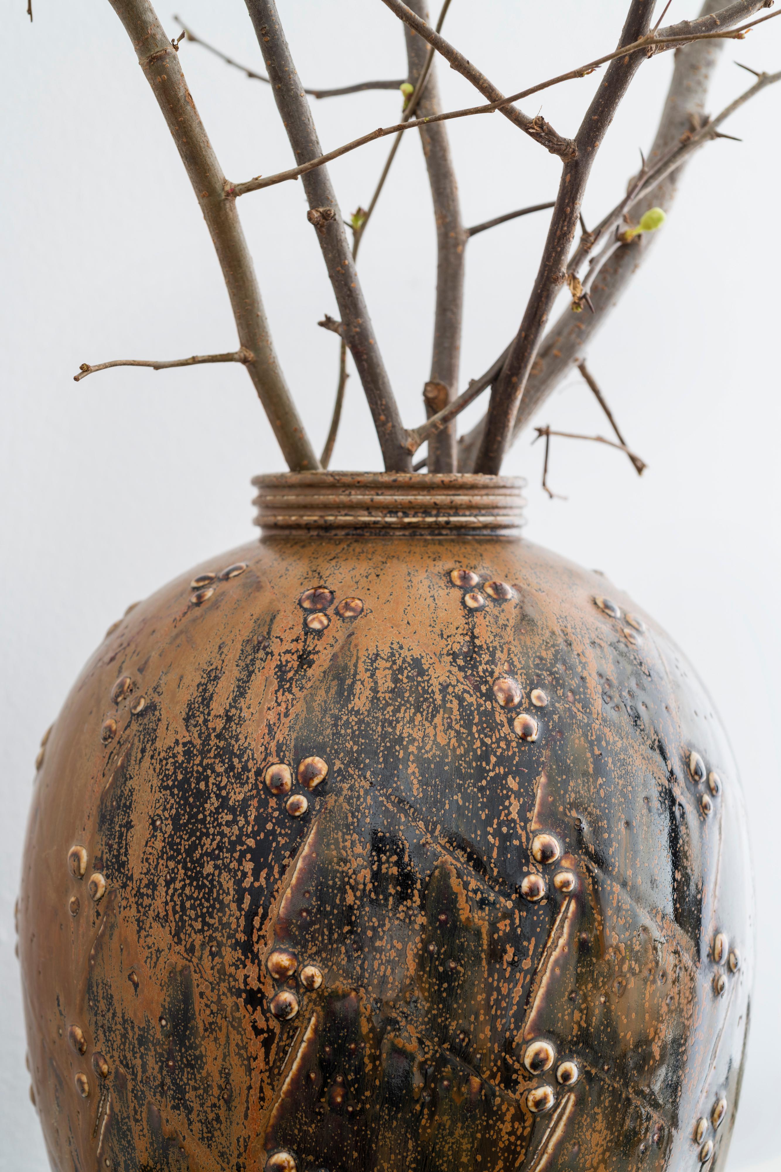 Large stoneware vase by Saxbo with matte rust glaze. There is heavy rust colored glaze on one side while the other side is a mix of black stoneware and rust. 

Base incised with stamp and marked 