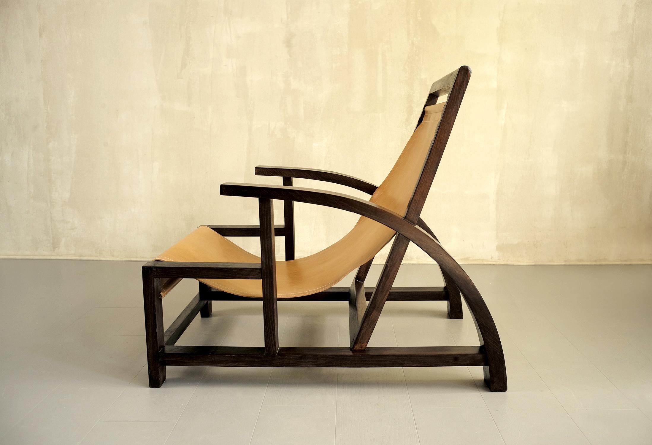 Grand fauteuil en bois noirci et cuir tendu, 1930. Le design moderniste alterne la courbe arquée des accoudoirs, la diagonale du dossier et les plans verticaux et horizontaux de la base. L'assise est constituée d'une bande de cuir naturel surpiquée,
