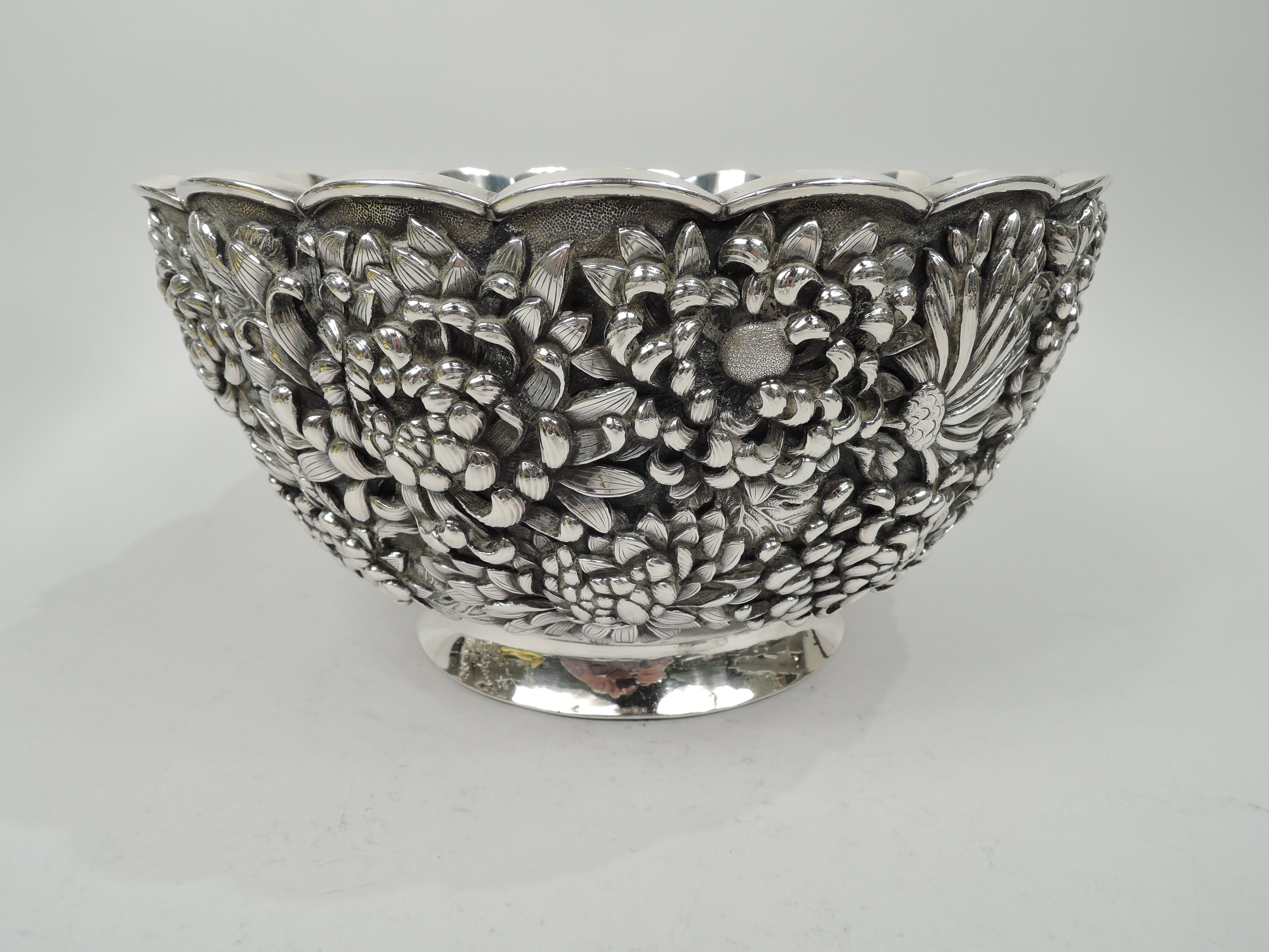 Large and striking Japanese Meiji silver bowl, circa 1890. Round with curved and tapering sides with dense and low relief Chrysanthemum flower heads with imbricated and tentacular petals. Plain scalloped rim and spread foot. Fluted double-walled