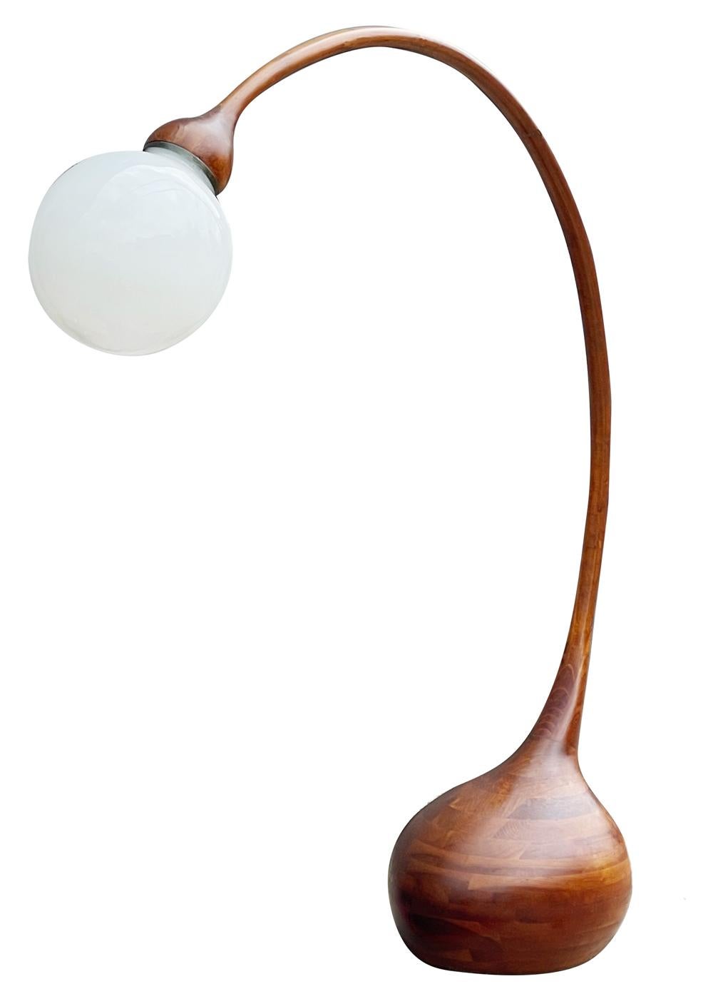 A large, impressive and sculptural floor lamp made by Robert Worth c.1970's West Chester PA. The lamp is entirely constructed of laminated hard woods, with brass lamp fitting and milk glass globe. Branded mark with signature.