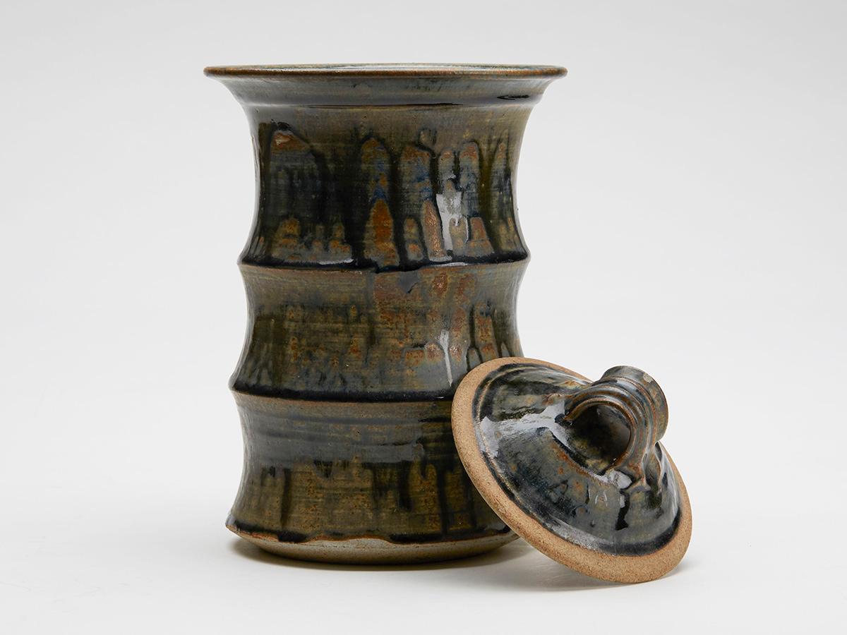 An exceptional and large Studio Pottery lidded jar of cylindrical form in three sections with a wide top rim and recessed domed cover. The jar is decorated with a brown wash applied with blue drip glazes. Despite the quality of this example it is