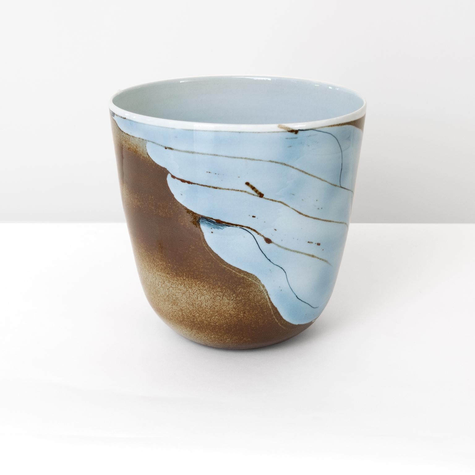 A large studio Inger Persson vase, bowl slightly oval form with a hand painted design in light blue and black on a brown and tan background, possibly an abstraction of a swan on water. Made at Rorstrand, Sweden, dated 1986. 

Measures: Height 10”,