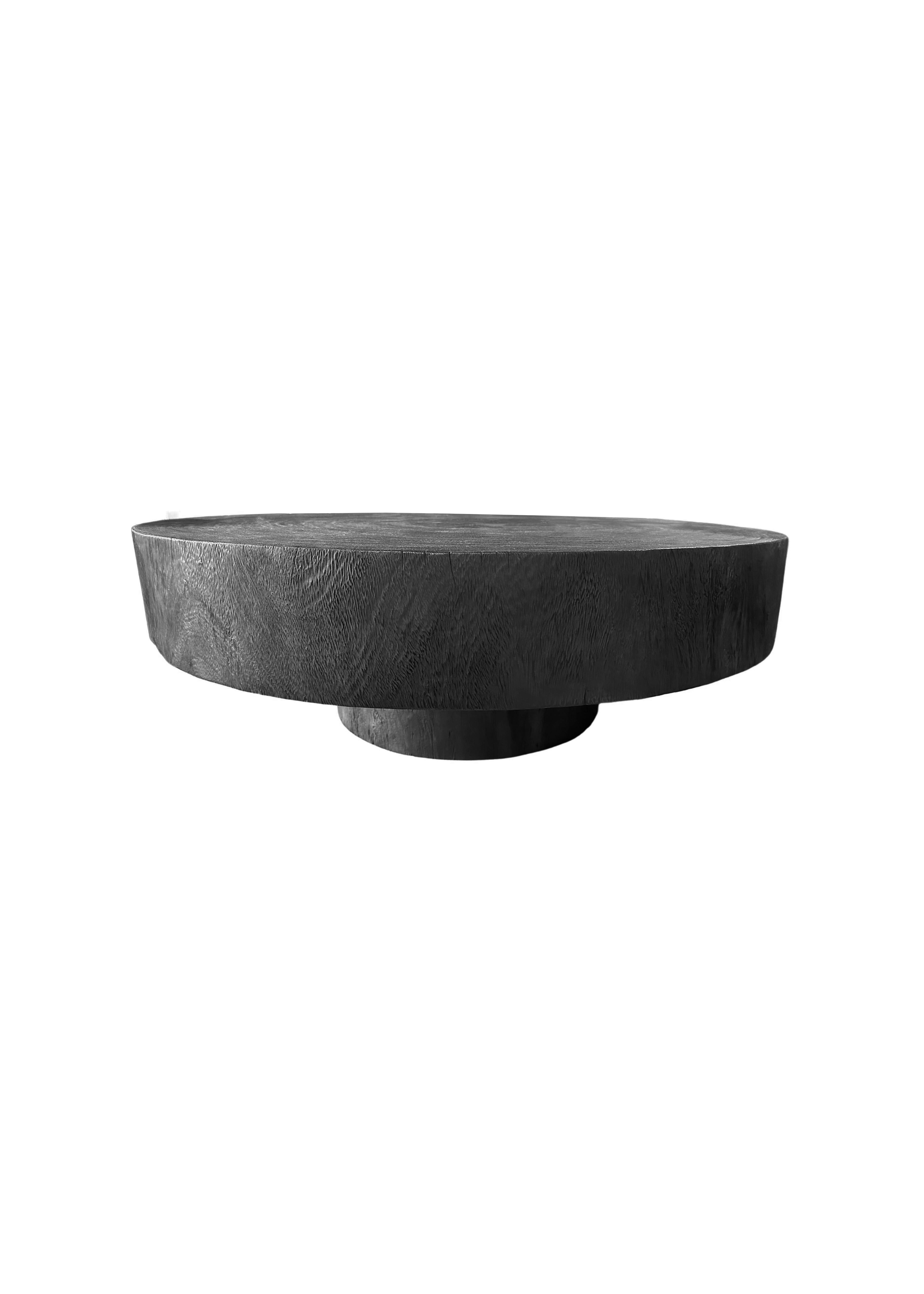 Un tavolo rotondo meravigliosamente scultoreo realizzato in legno di suar. Per ottenere il pigmento, il legno è stato bruciato numerose volte e poi rifinito con una vernice trasparente. Il mix di texture e tonalità del legno ne aumenta il fascino.