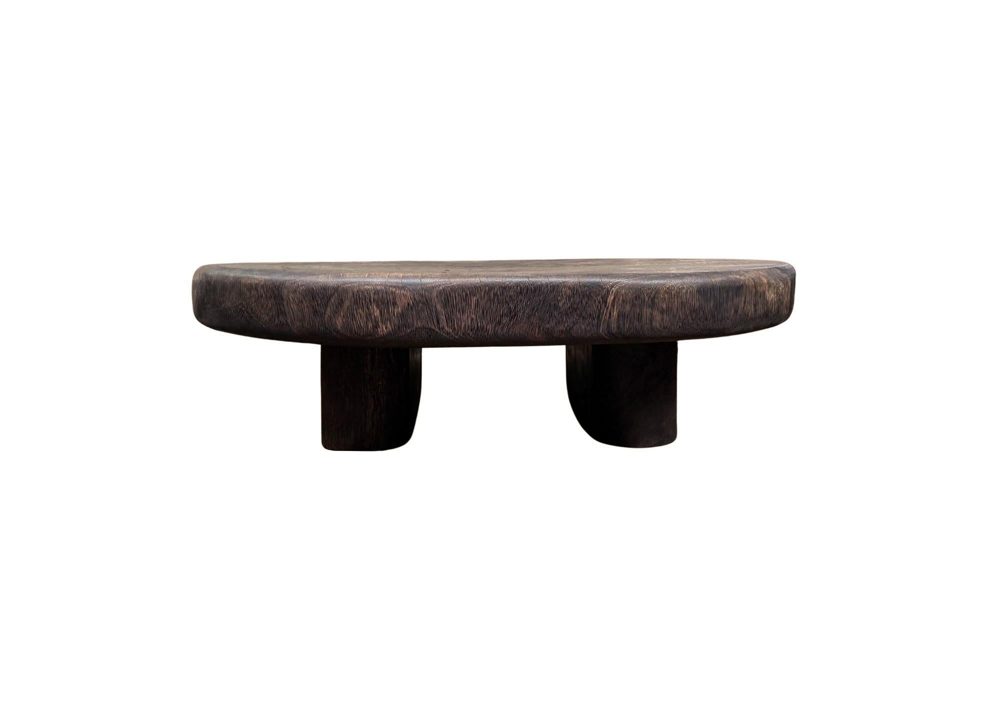 Fabricada en madera maciza de suar, esta llamativa mesa presenta una silueta orgánica y redondeada que muestra la belleza en bruto de la naturaleza. El acabado marrón oscuro espresso realza las impresionantes vetas naturales de la madera, dando a