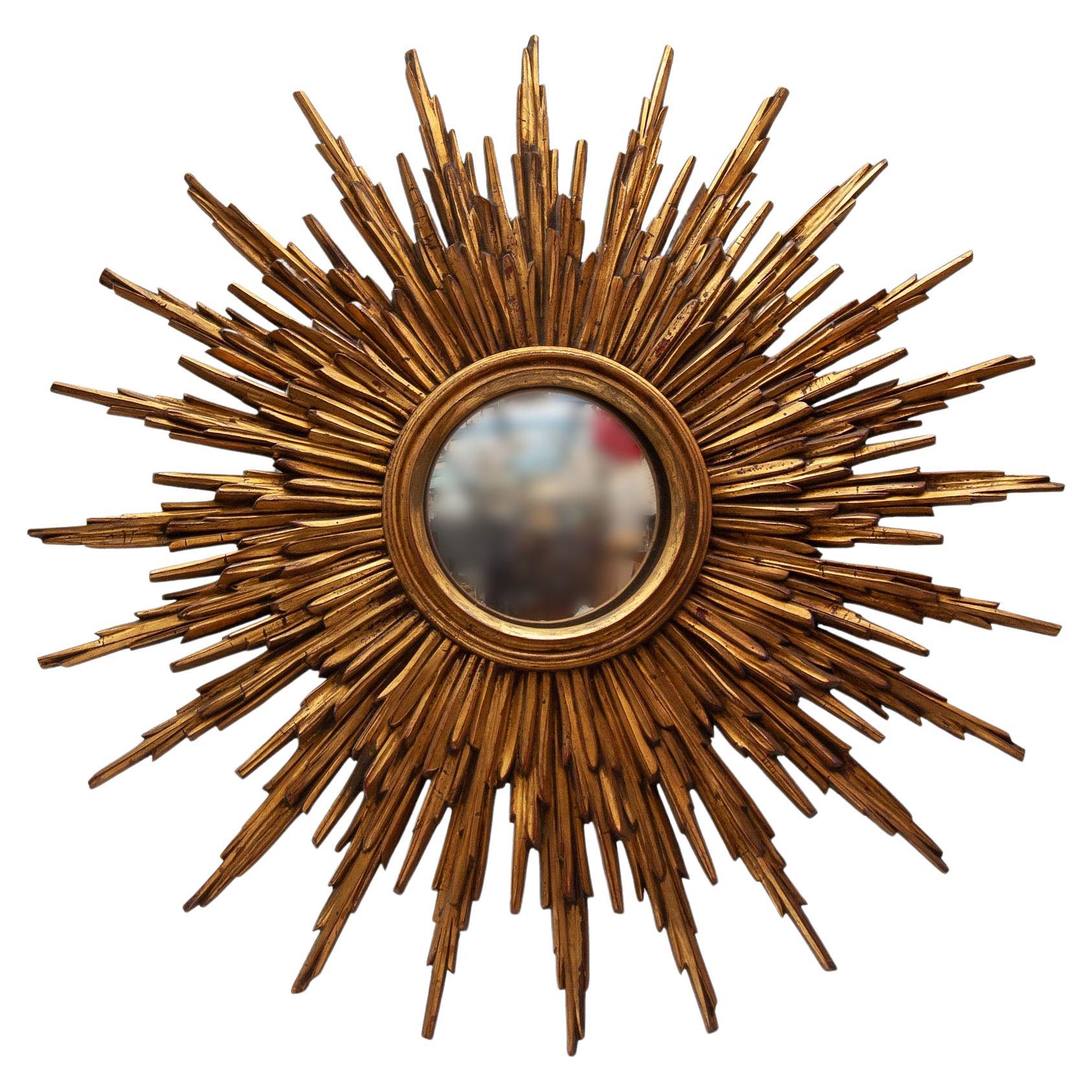A vintage French gilt wood sunburst mirror from 1930s, with layered rays and small mirror plate. Created in France during art deco period, this sunburst mirror features a central mirror plate surrounded by a cloudy frame resting on a first layer of