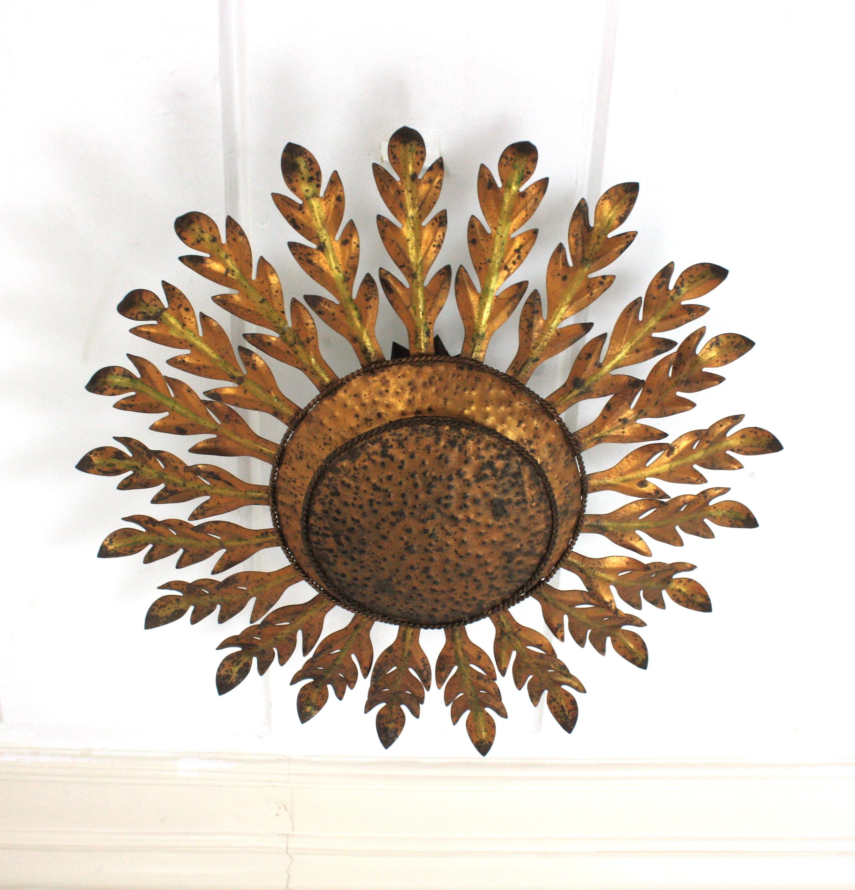 Spanische Einbaubeleuchtung mit Sonnenschliff und Blattwerk, Schmiedeeisen, vergoldetes Eisen
Spanien, 1950
Skulpturale Sonnenschliff-Deckenleuchte mit Blattrahmen, der eine zentrale kugelförmige Platte umgibt, Eisen vergoldet, Blattgold
Diese