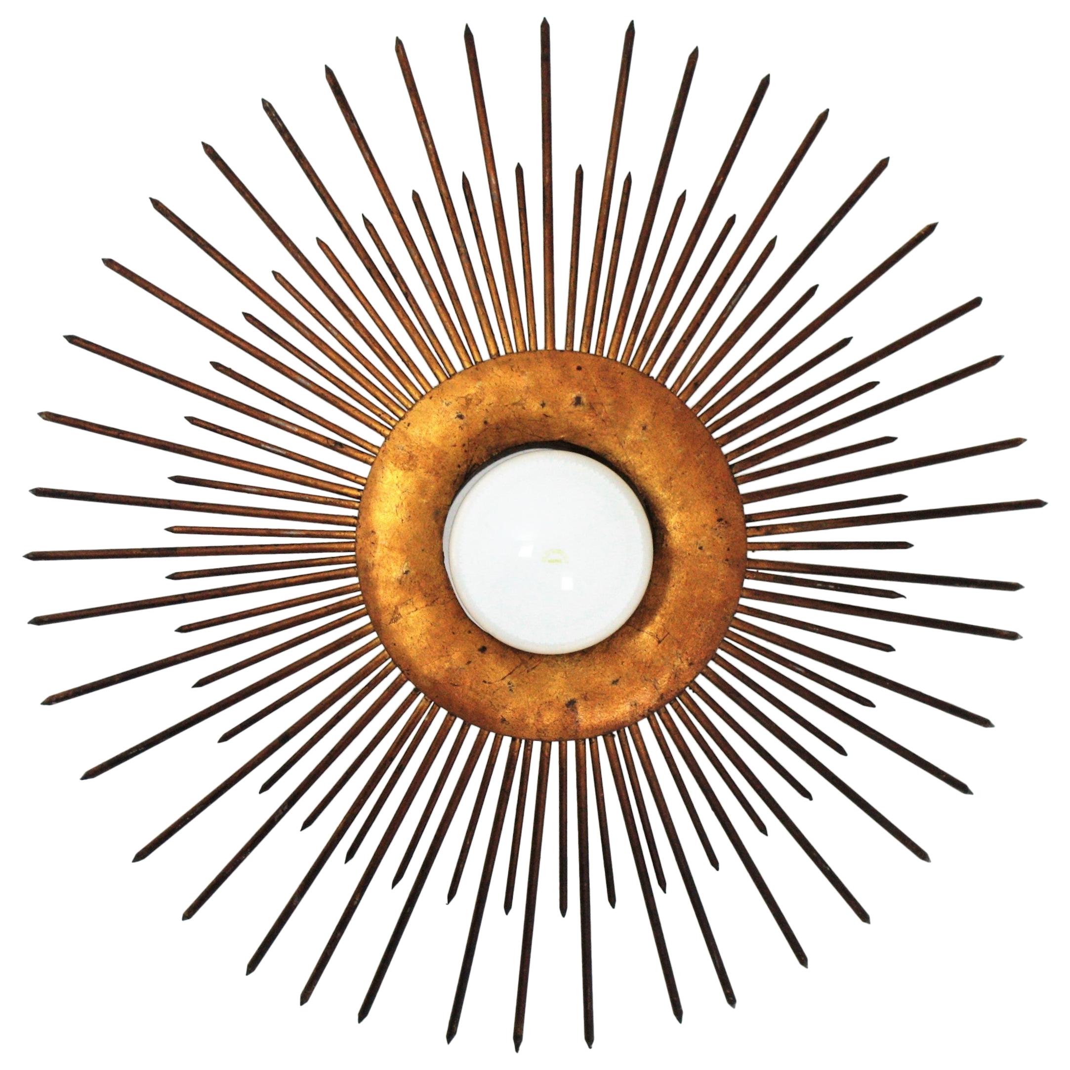 French wrought iron bronze gilt large sunburst flush mount or pendant, 1930s-1940s
A highly decorative sunburst shaped ceiling light fixture with frontal light. It has iron nails in two sizes as sun beams surrounding the central sphere and a design