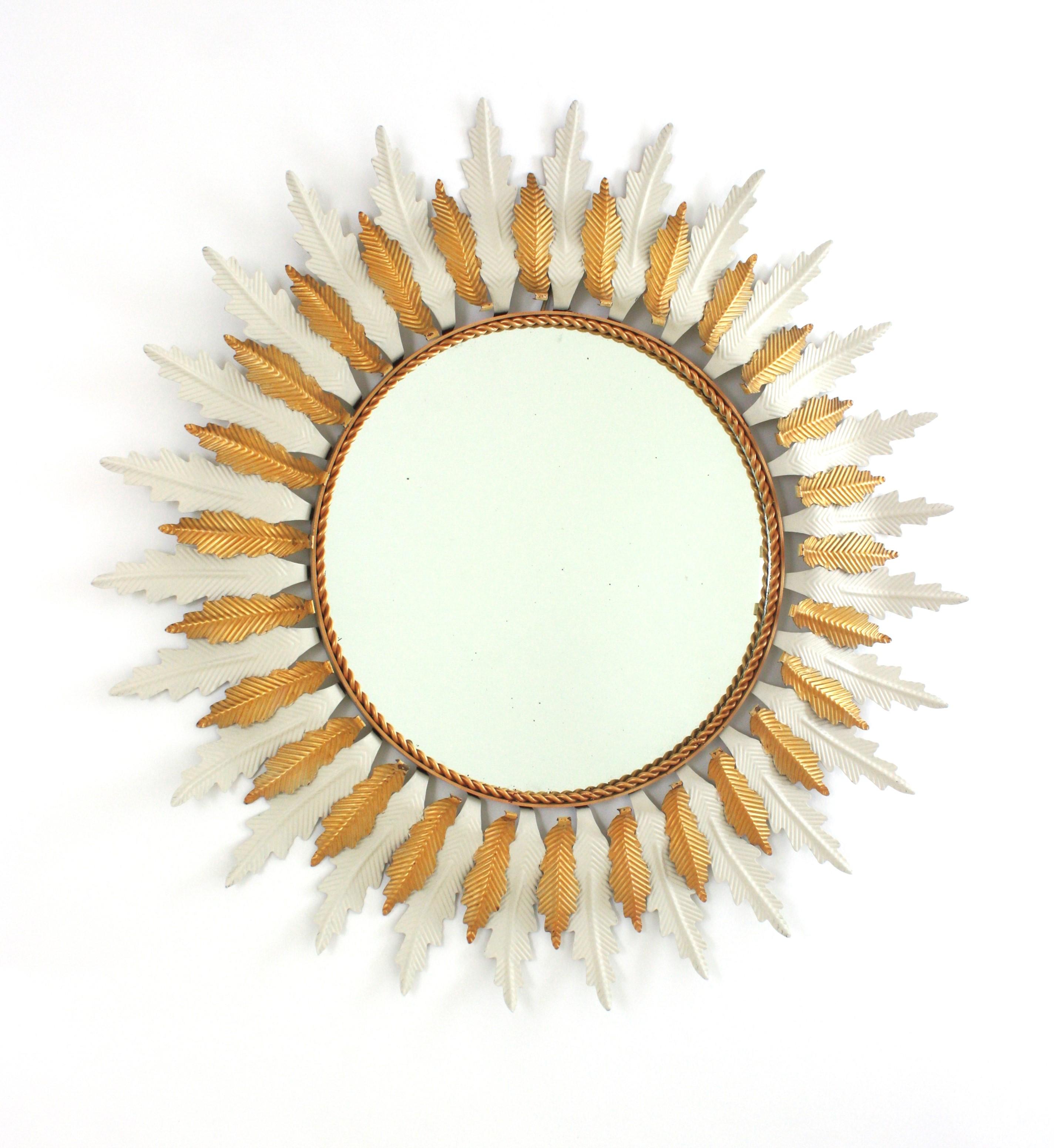 Mid-Century Modern Two-Tone Sunburst Flower Wall Mirror, white and gilt metal frame. Spain, 1960s.
This wall mirror features a layers of white lacquered leaves alternating with another layer with gilt leaves surrounding a central glass.
Rare