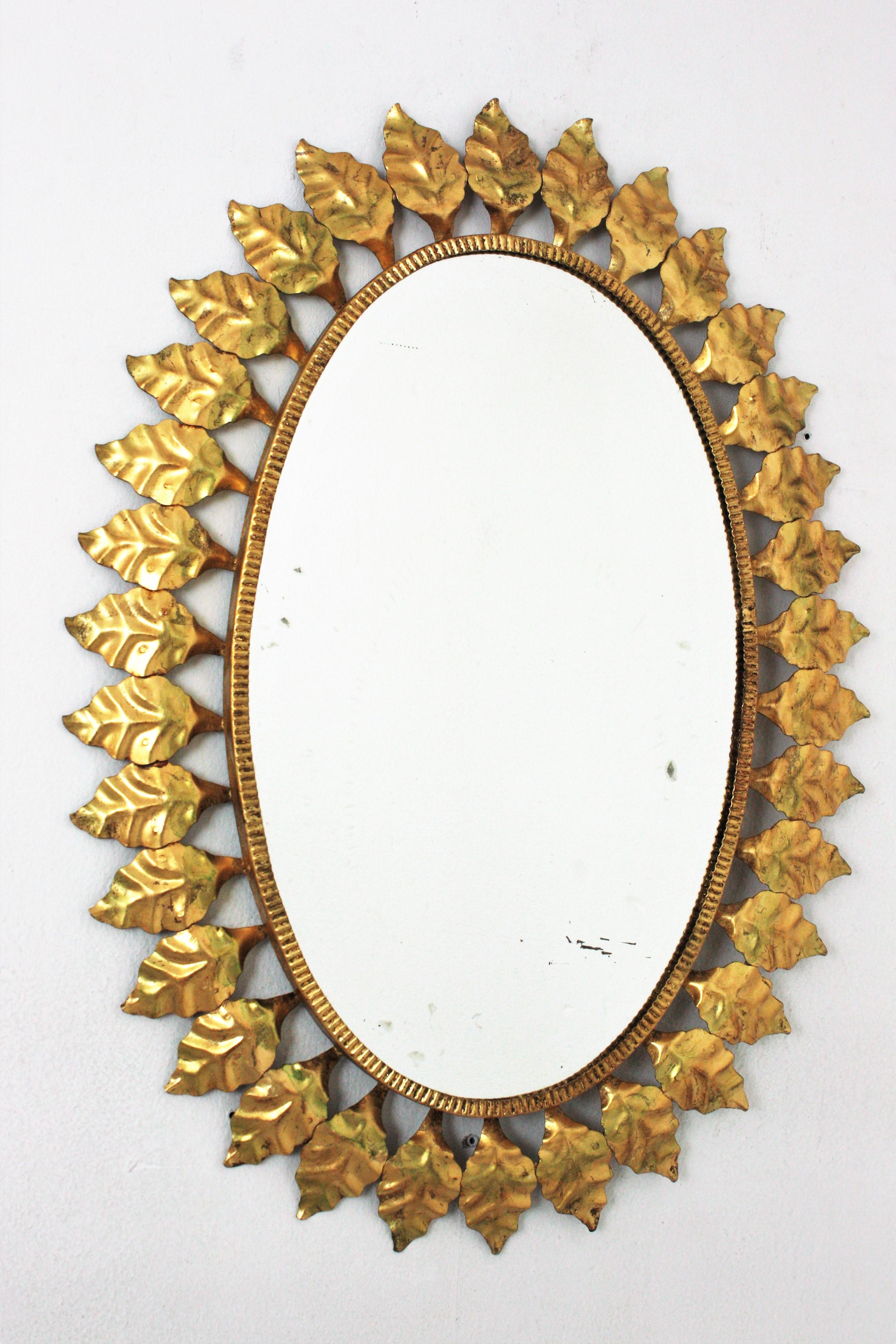 Ovaler Spiegel mit Sonnenschliff aus vergoldetem Eisen, 1950er Jahre (Hollywood Regency) im Angebot
