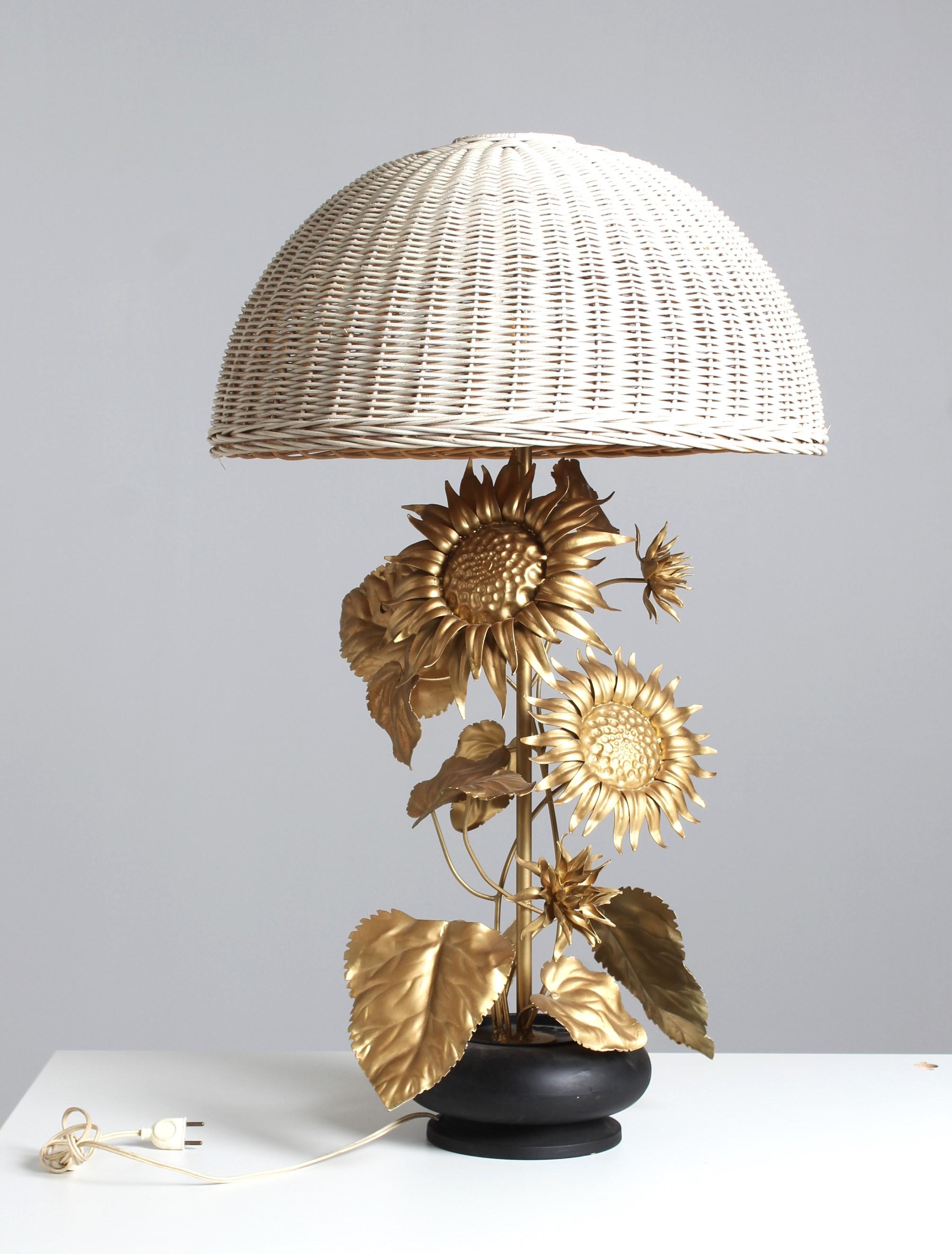 Große Sonnenblumen-Tischlampe aus goldlackiertem Metall mit detaillierten Blüten und Blättern.
Die Pflanze ragt aus einem Blumentopf heraus und wird von einem Rattanschirm gekrönt.

Höhe 95 cm
Durchmesser des Lampenschirms: 57 cm

Die