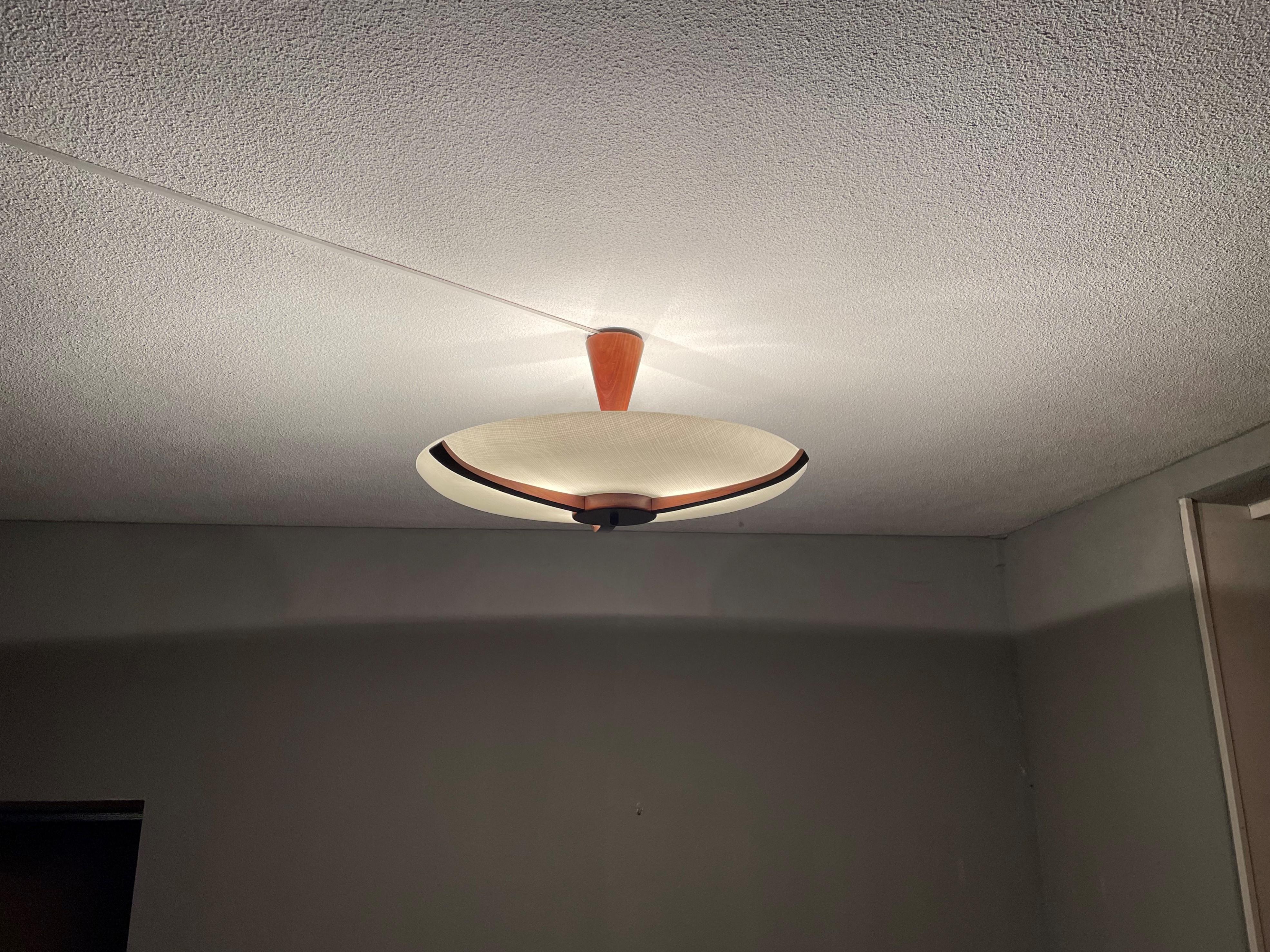 Great Mid-Century Modern ceiling light with teakwood and 'woven' pattern in the glass shade.

This vintage, three-light flush mount has a beautiful look and feel and you will hardly ever find a light fixture from the Mid-Century Modern era with a