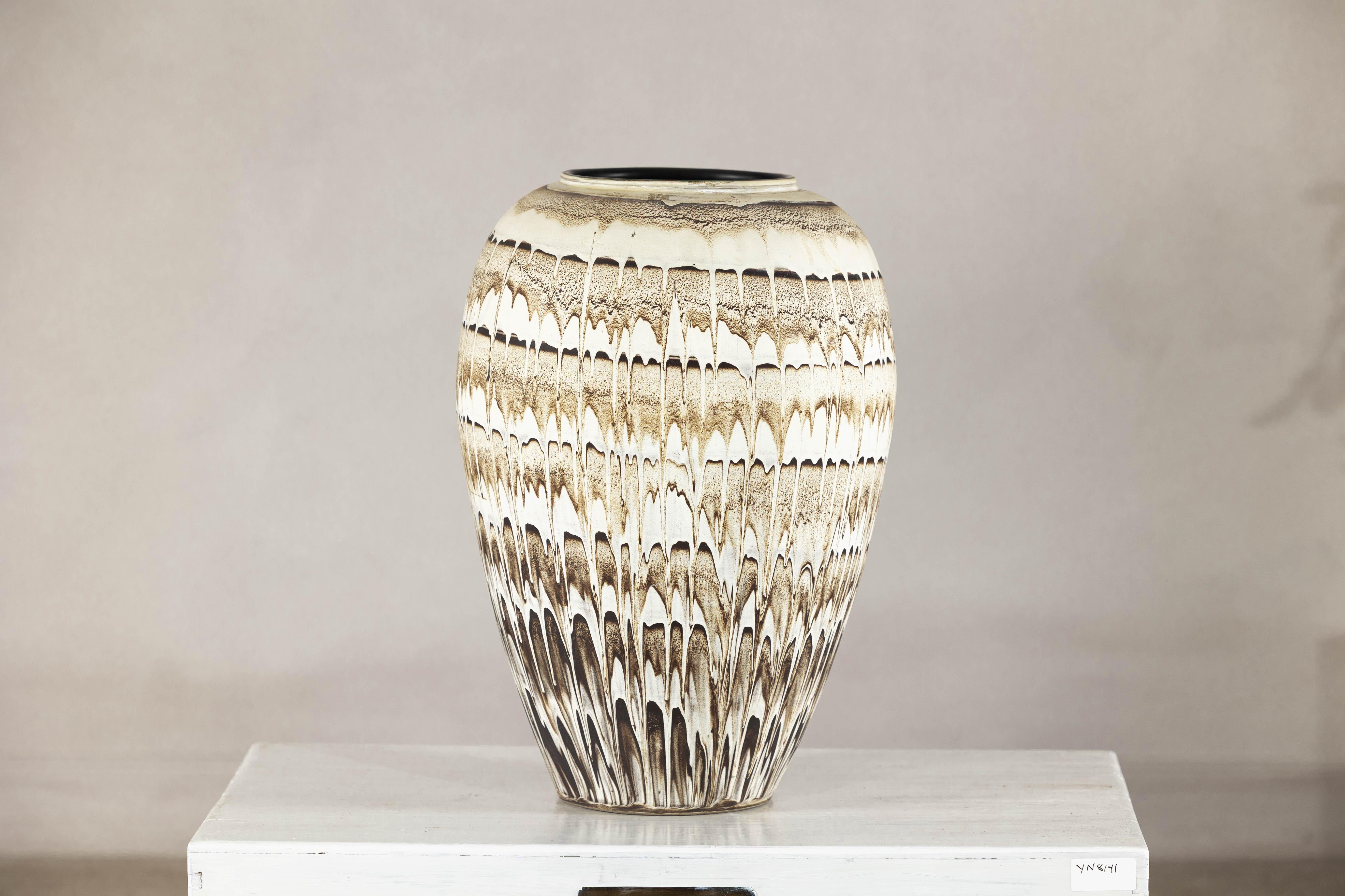 Avec sa surface frappante et sa taille généreuse, ce grand vase ou cache-pot en céramique offre une réinterprétation contemporaine du style Swankhalok, une esthétique enracinée dans les anciens fours thaïlandais de Sukhothai. Sa forme ovoïde est à