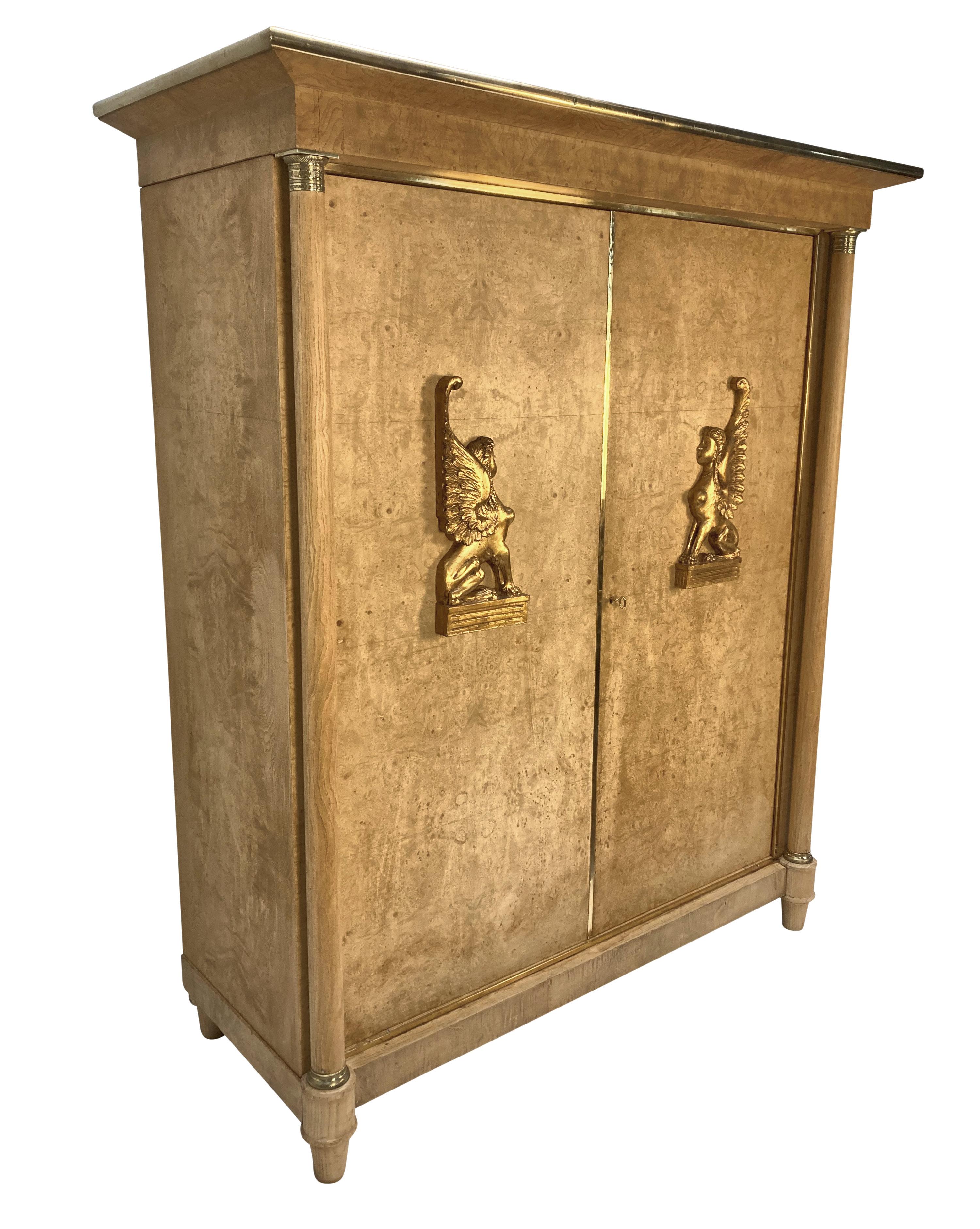 Gran armario de dos puertas de estilo Imperio sueco de gran calidad, revestido de roble y chapado de arce blanqueado, con dos esfinges talladas en madera dorada. Hay bordes de latón por todas partes y detalles en las dos columnas. El armario se abre