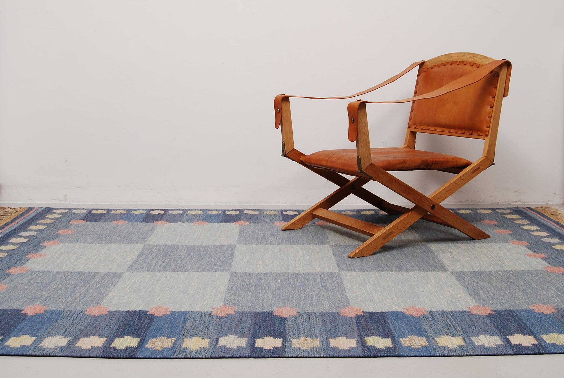 This flat weave / rölakan / kelim carpet was designed by Anna Johanna Ångström and made by hand in Sweden. This example with fields in different shades of blue, and some elements of pink, beige and light brown was woven in wool and are signed ”Å” to