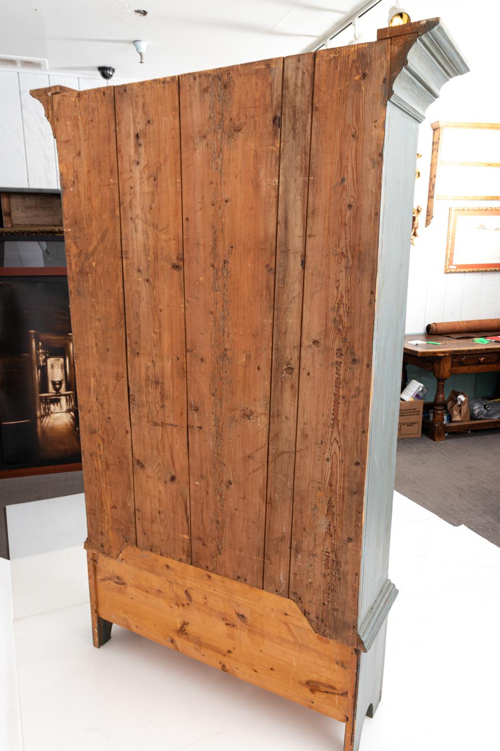 Large gray painted cupboard with square pediment, circa early 1800s. The piece features a two-door cupboard with interior shelving and two drawers. The lower half includes another drawer. Please note of wear consistent with antique age including