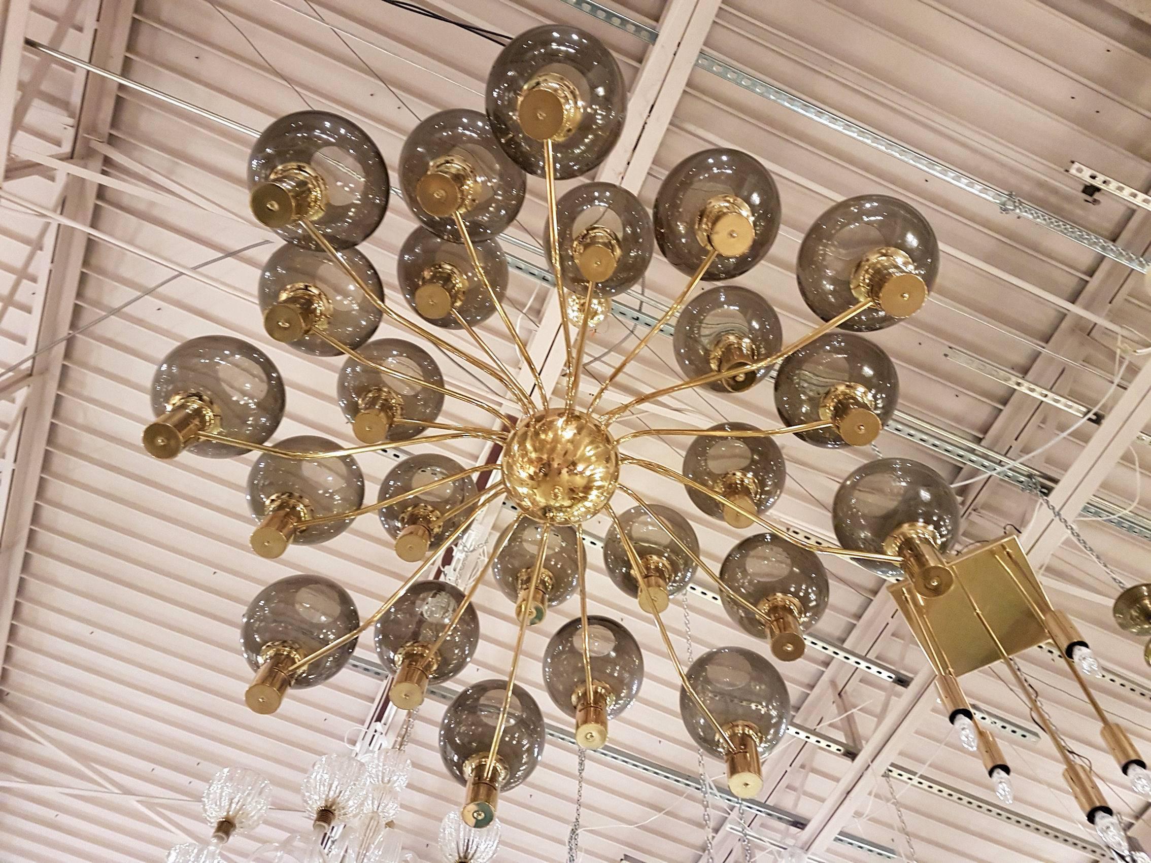 Swedish Mid-Century Modern chandelier attributed to Hans-Agne Jacobsson with 24 brass arms capped by transparent, grey glass globes.