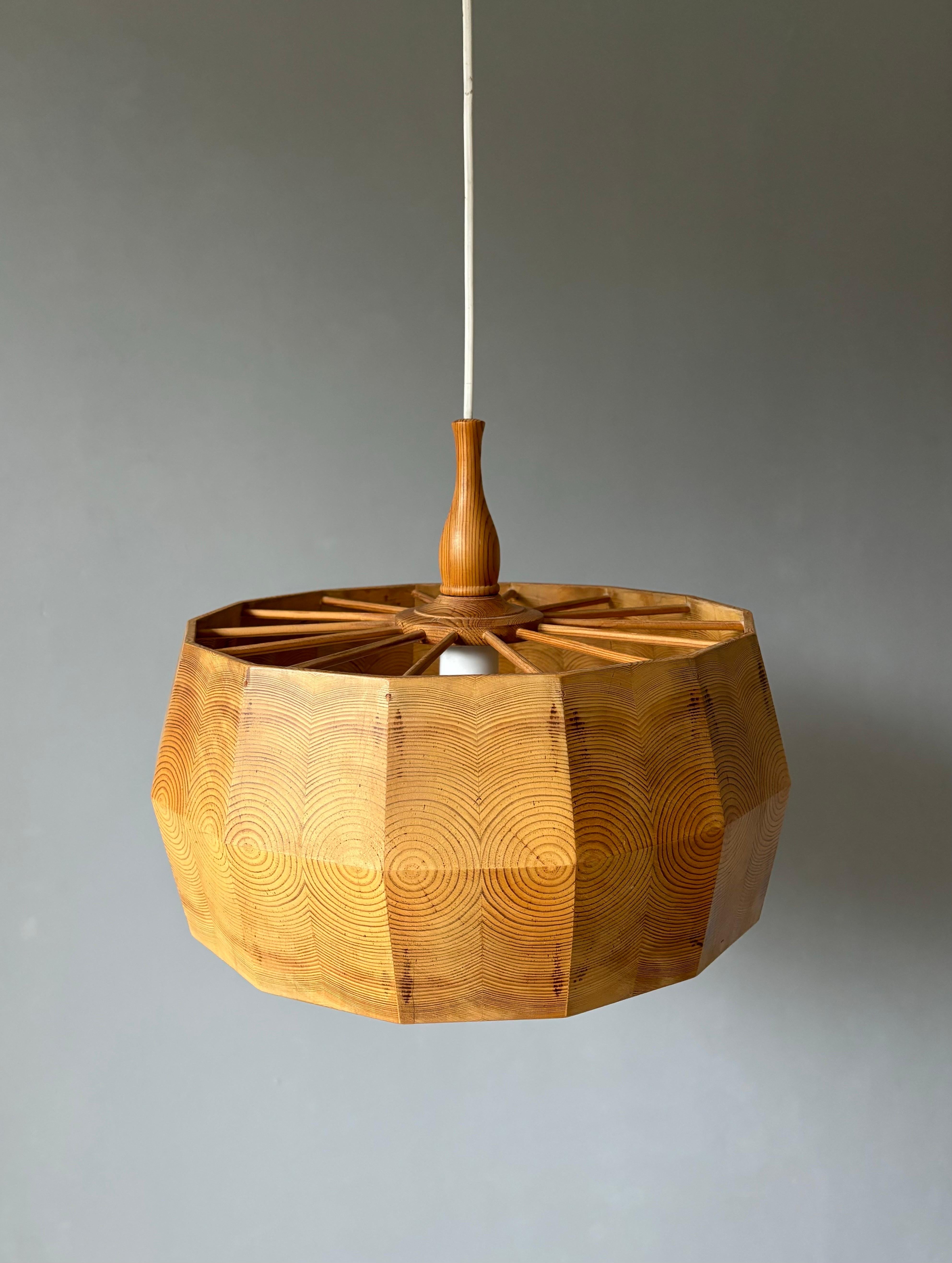 Pendente in legno di pino, realizzato a mano, prodotto in Svezia negli anni '60 e attribuito all'acclamato designer Yngve Ekström. Forme angolate che mettono in evidenza i motivi circolari del legno di pino e aste sottili che accentuano la forma