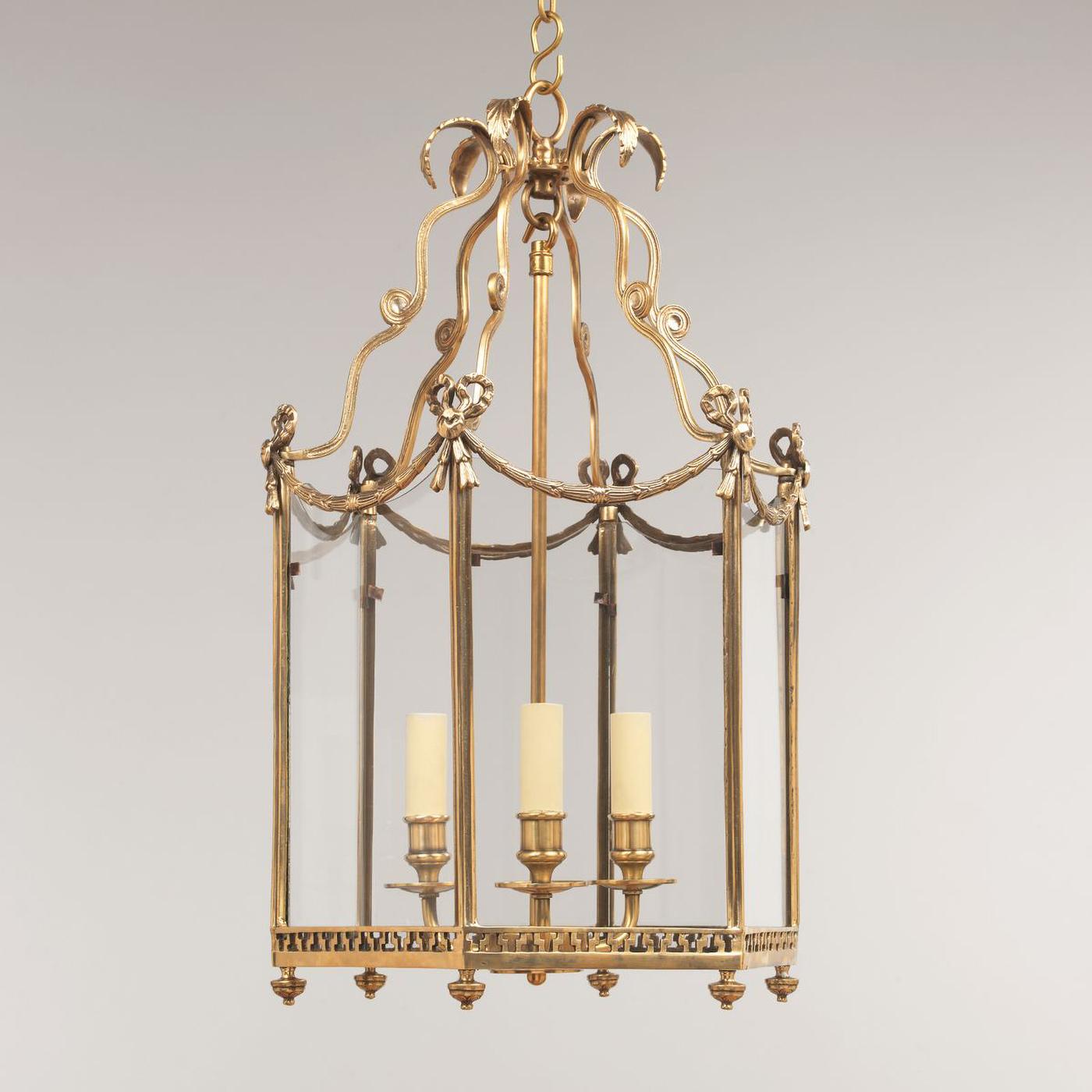 A small Swedish Neo-Classic style five-light brass hall lantern with 18th-century style embellishments. The leaf tip crown above scrolling supports and a hexagonal frame decorated with bowknots, tassels, and bellflower swags. The base is decorated