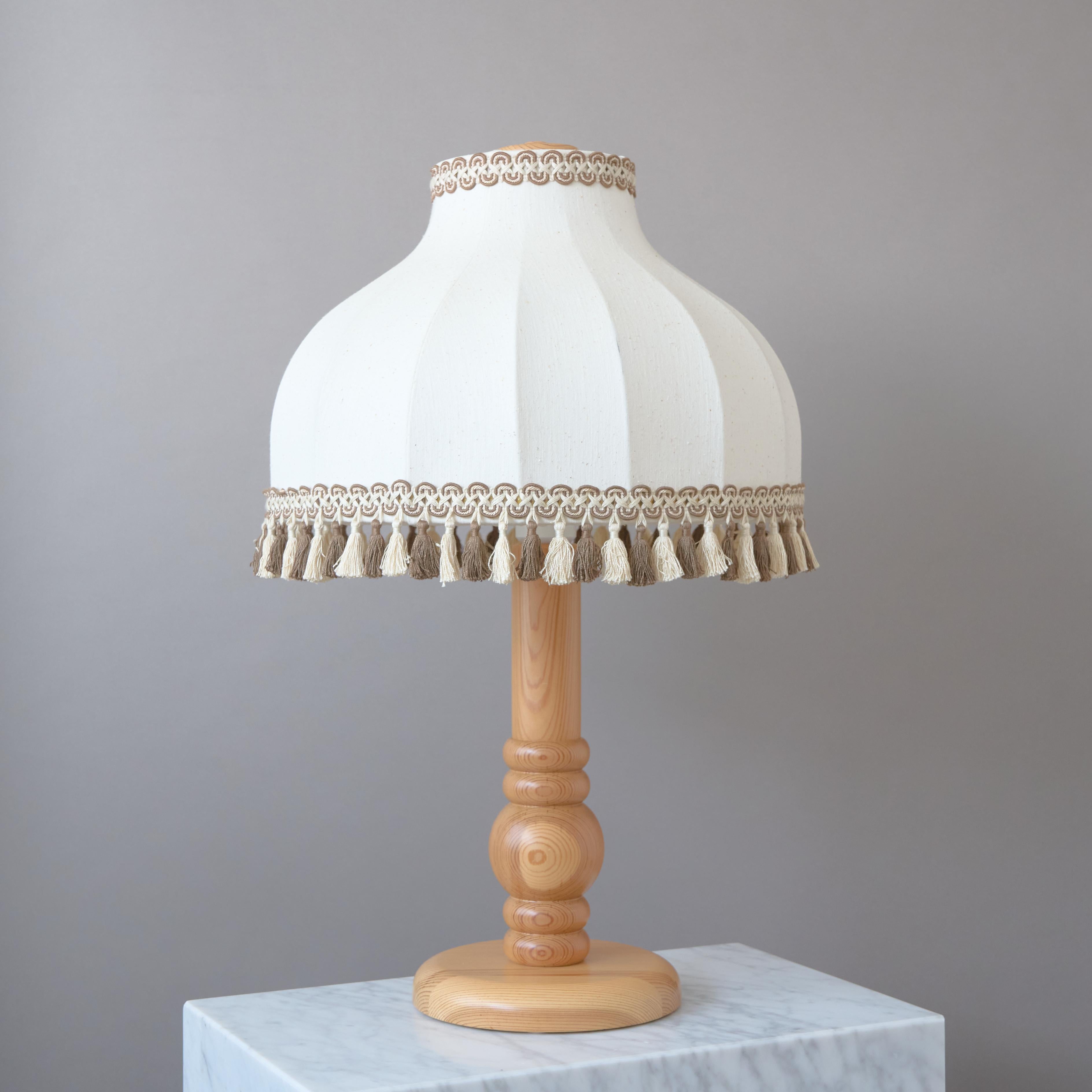 A large and beautiful pine wood table lamp, with original fabric shades and lace trim.

Made by Trivsel Belysning AB in Sweden, 1970s.

Great original condition. Labeled.
Sold with the original lampshade.

Light source: E26/E27 screw bulb.
Number of