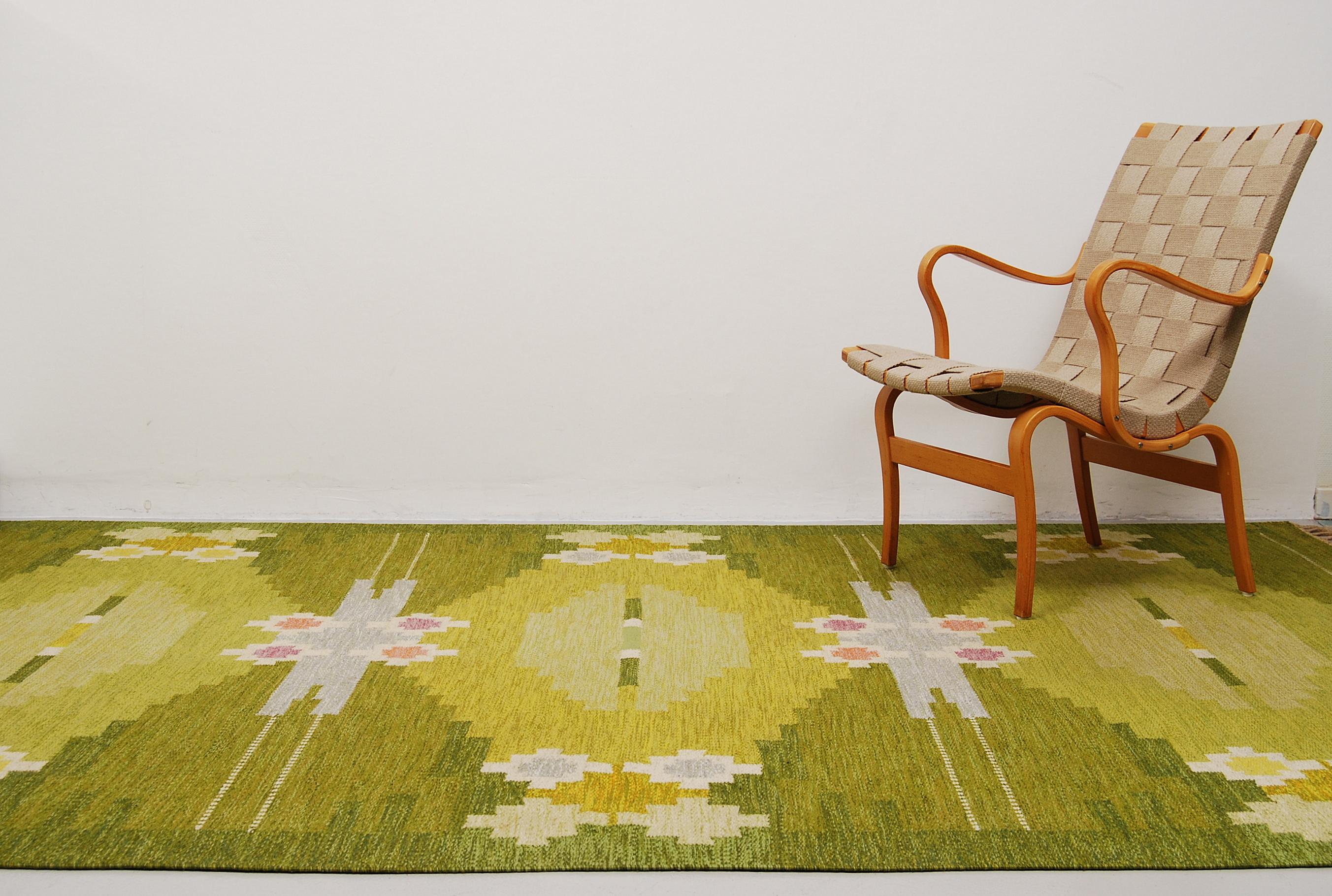 A large flat-weave rölakan carpet designed by Ingegerd Silow, Sweden. Handwoven with a geometric pattern where the colors are different shades of green, yellow, pink and purple. Signed IS in the right hand corner. Professionally hand-washed.