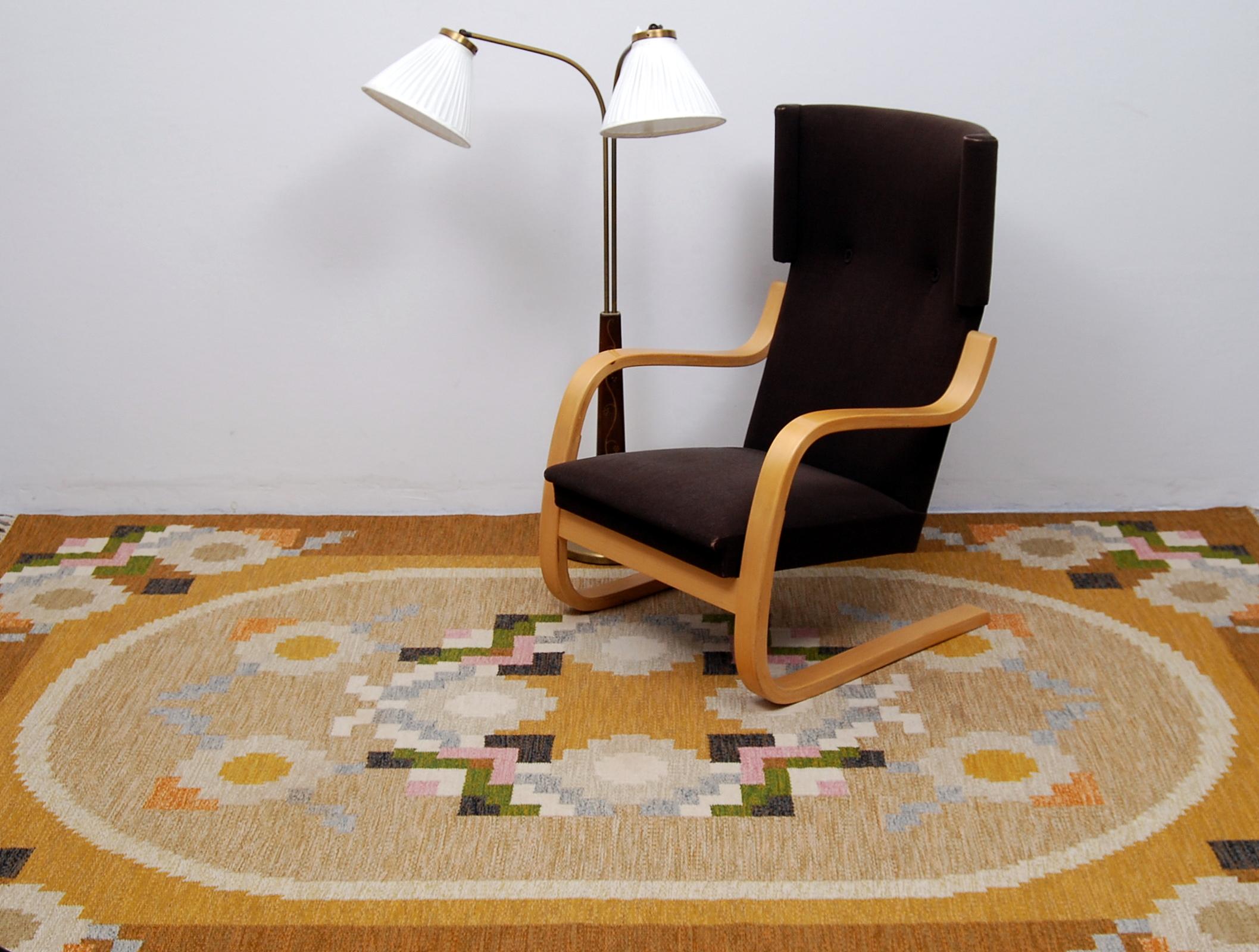 A large flat-weave rölakan carpet designed by Ingegerd Silow, Sweden. Handwoven with a geometric pattern where the colors are different shades of brown, yellow, pink, green, blue and white. Signed IS in the right hand corner. Professional