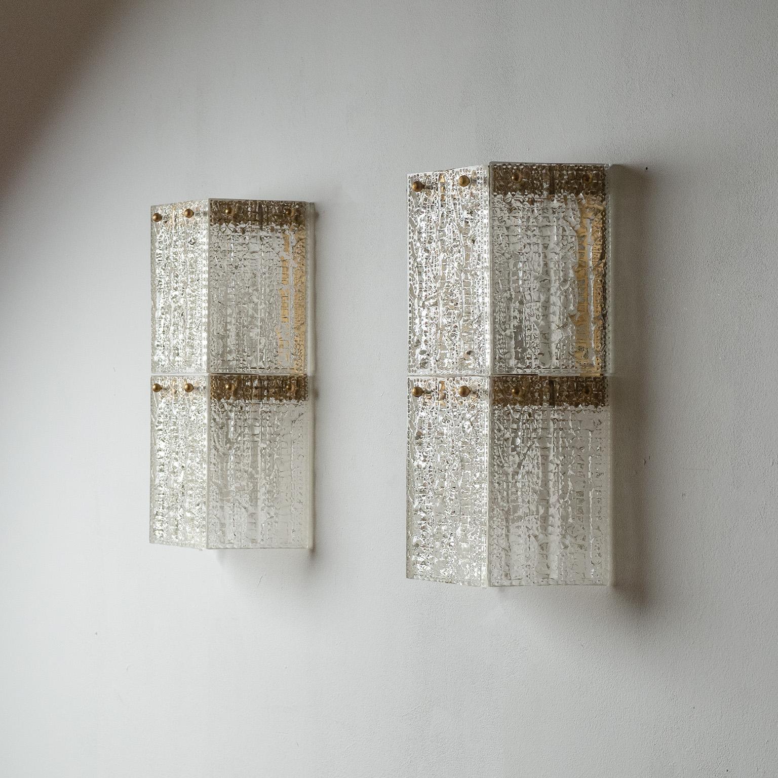 Large Swedish textured glass sconces from the 1960s, attributed to Orrefors. Semi-hexagonal shape with six heavily textured glass panes attached to a minimal brass structure. Two E27 sockets per light. Priced and sold as a pair.
Measures: Height