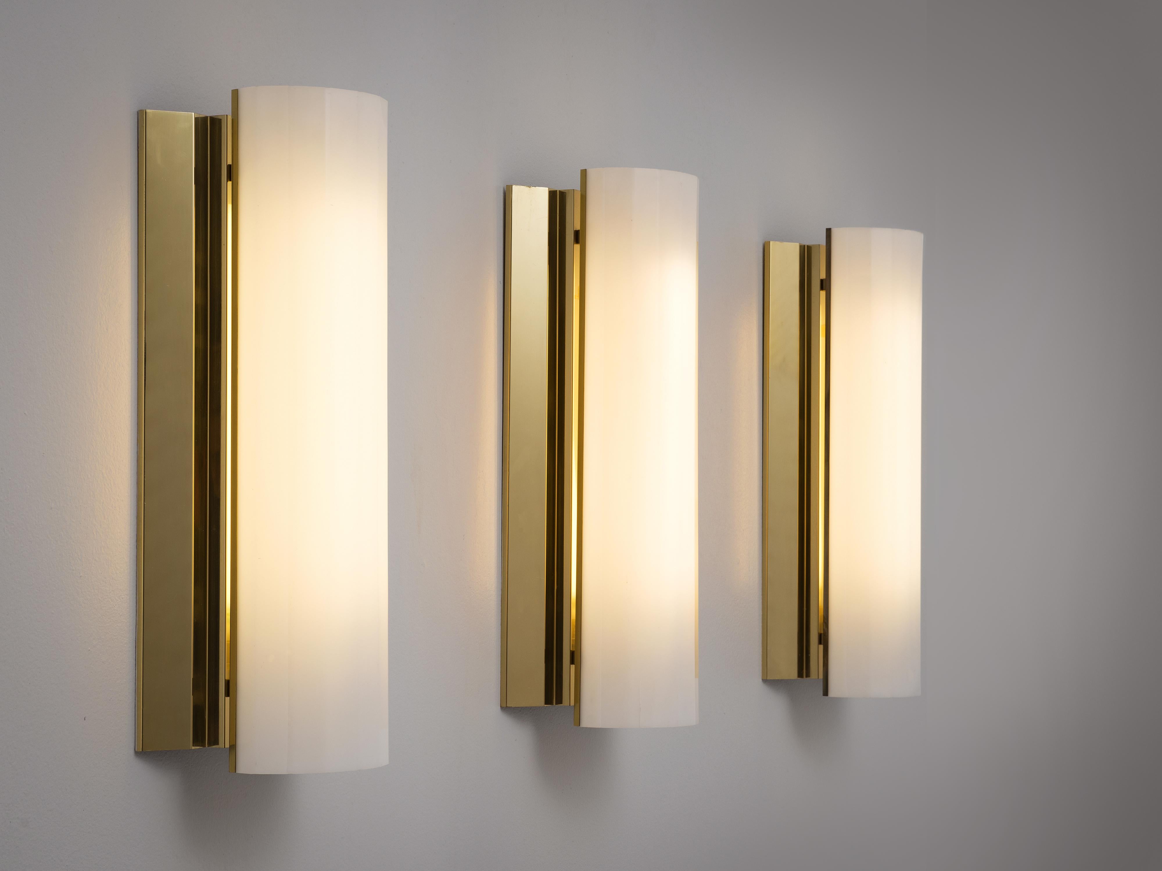 Wall lights, brass, plastic, Sweden, 1970s. 

Set of three large wall lights. Each light consist of a large brass holder with a polygon shaped white Lucite shade. Due the combination of materials these wall lights will create a beautiful warm and