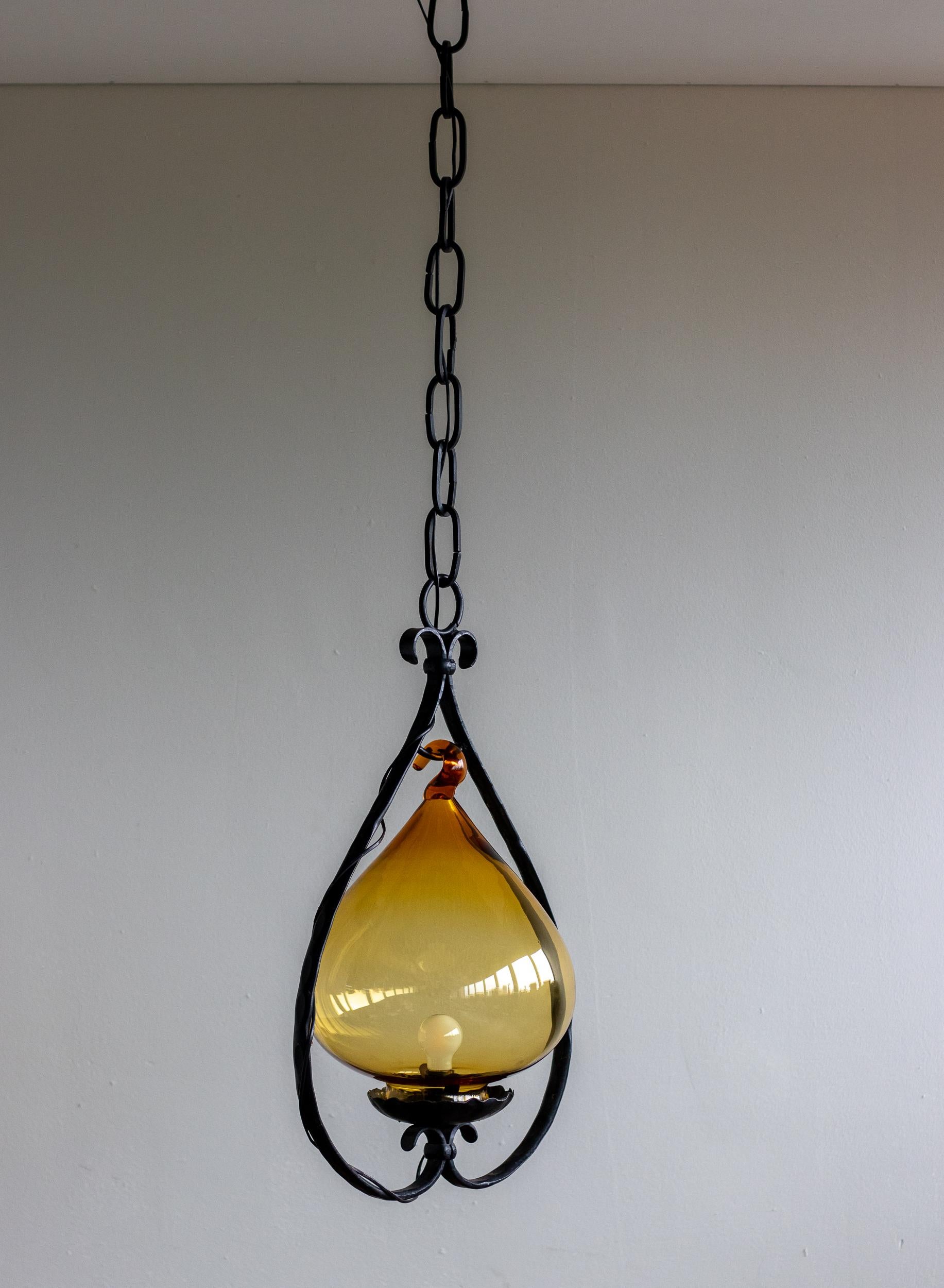 Unique vintage honey colored glass pendant attributed to Erik Hoglund. Glass shade made by Boda Nova Glassworks; wrought iron frame made by Axel Stromberg Ironworks, Sweden, circa 1957. 

Erik Höglund was a Swedish artist and designer known for
