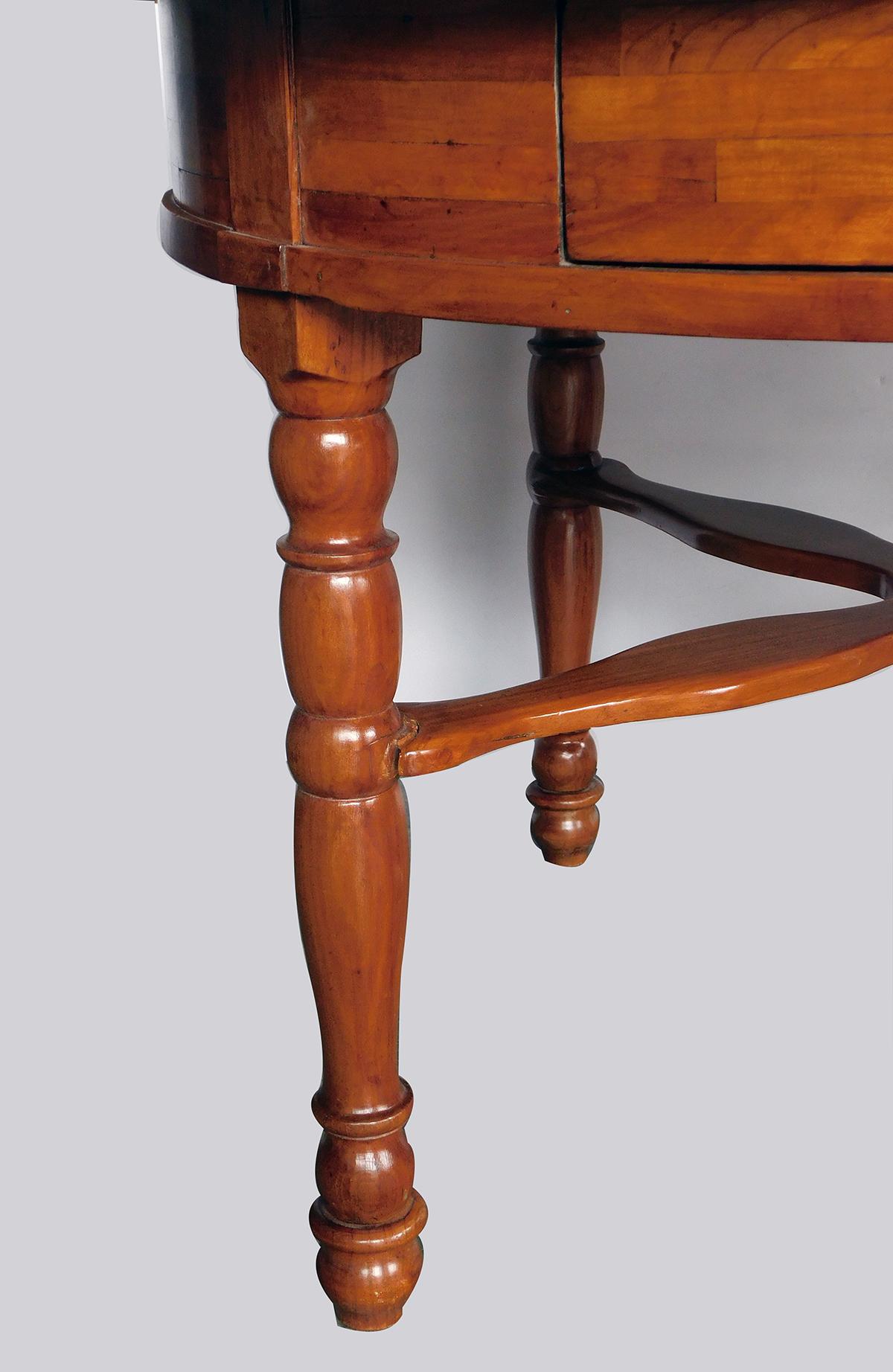 Of warmly patinated cherrywood, the circular top above a deep apron fitted with a single drawer; all raised on turned supports joined by a shaped x-form stretcher.