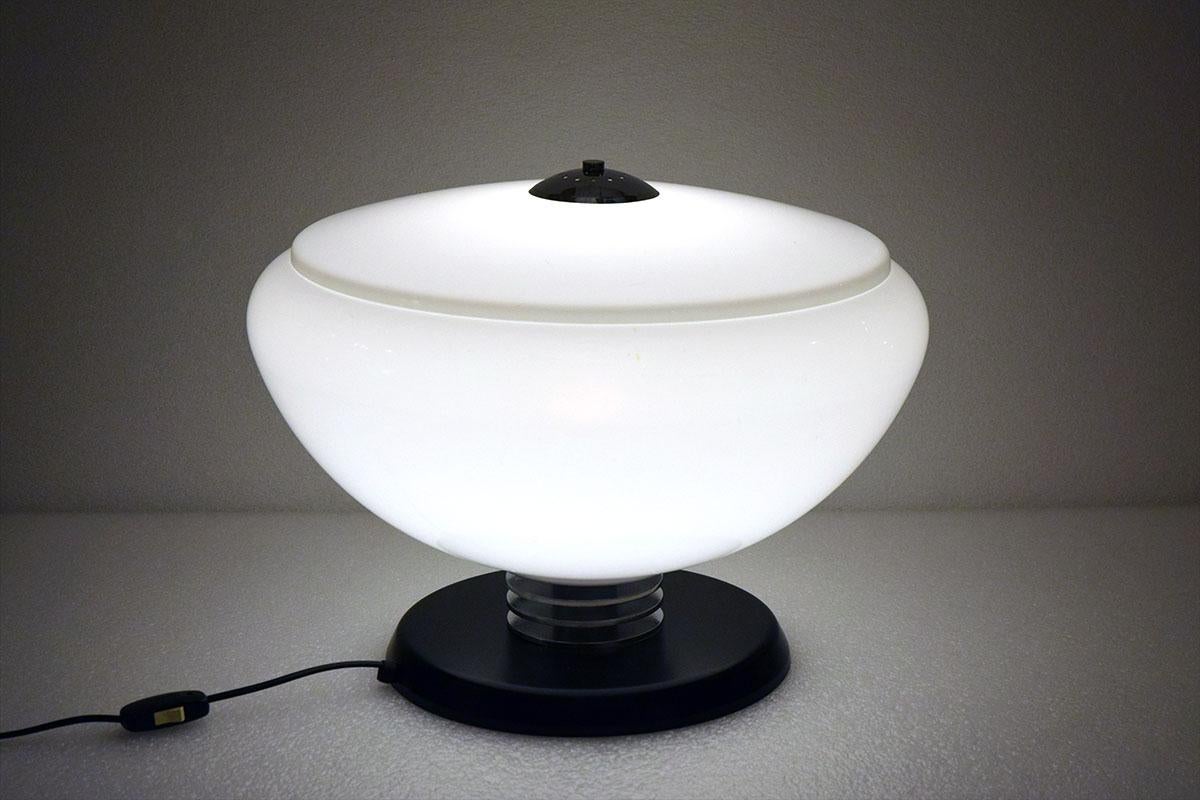 Large table lamp attributed to Guzzini 1970s.
Painted metal foot with chromed metal discs, perpex diffuser in white color in two parts with cover.
In excellent condition.