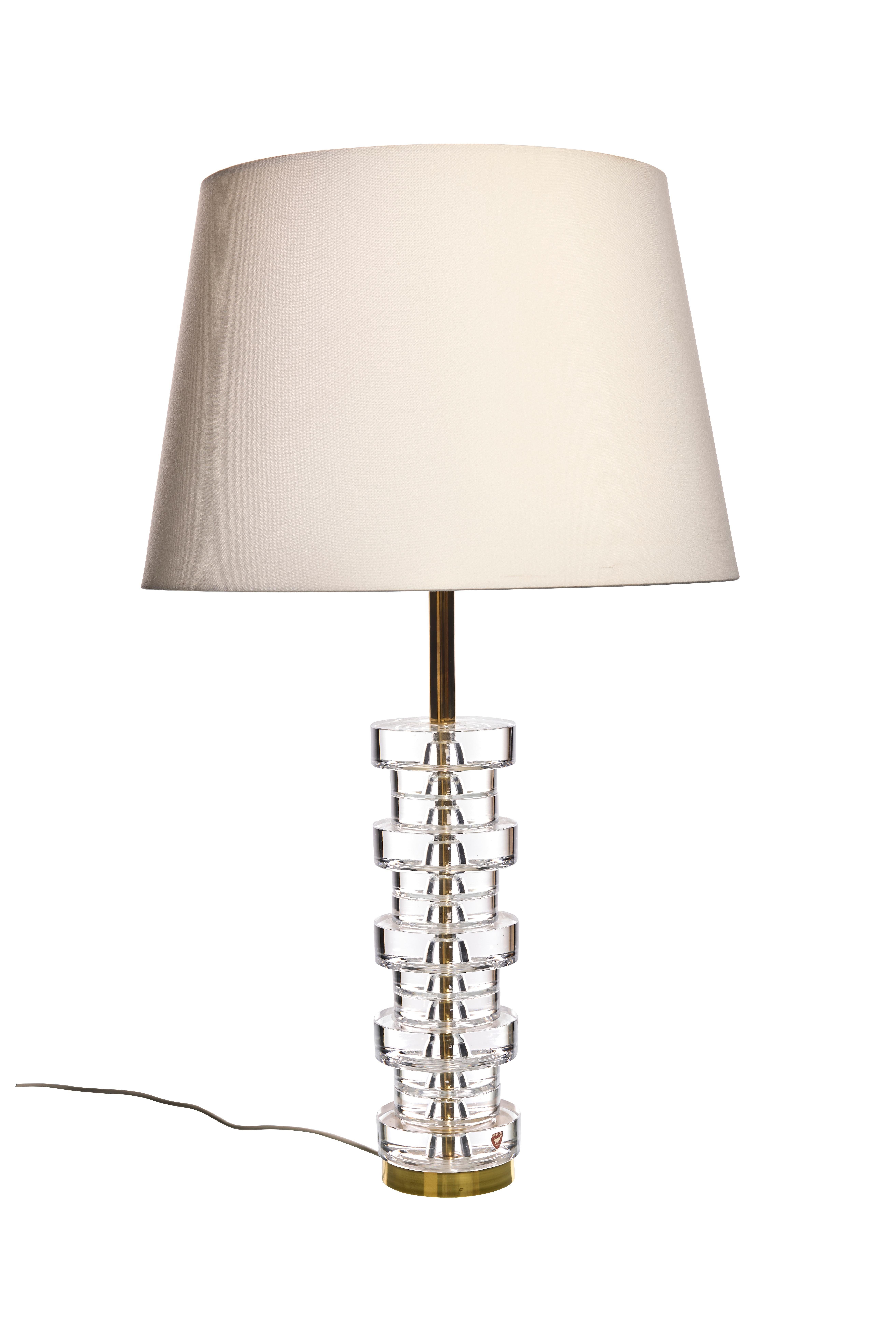 Elegante lámpara de sobremesa de Carl Fagerlund para Orrefors. El elegante diseño de las lámparas las hace adecuadas para todos los estilos de interior.
La lámpara consta de 13 discos de cristal transparente, apilados unos sobre otros sobre una base