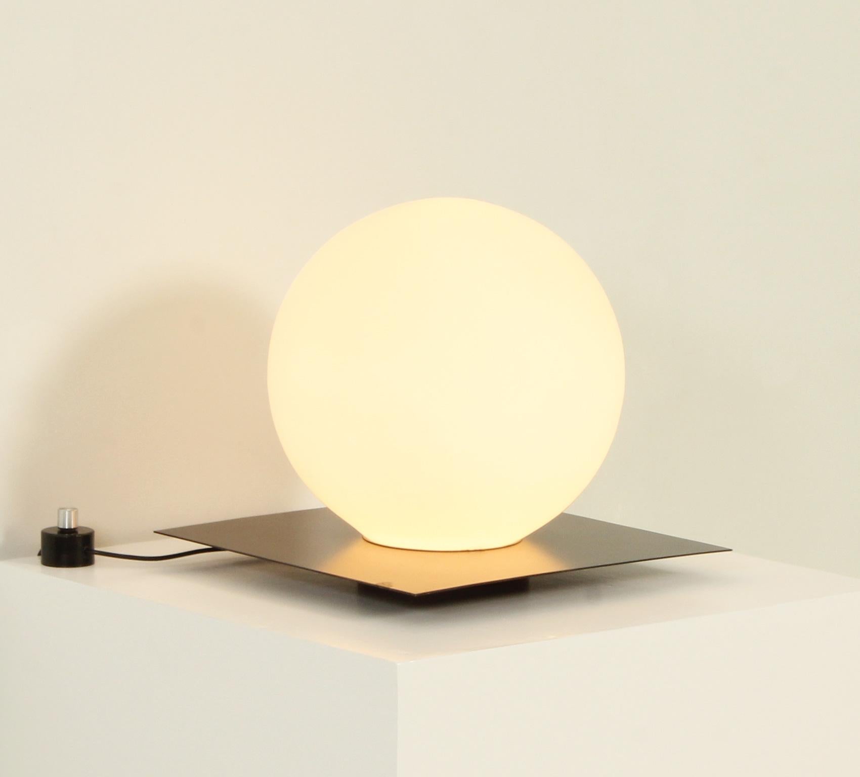 Grande lampe de table produite par Carpyen, Espagne, années 1970. Design minimal avec une base en métal noir et un globe en verre opale soutenu à la base. L'intensité lumineuse peut être régulée.