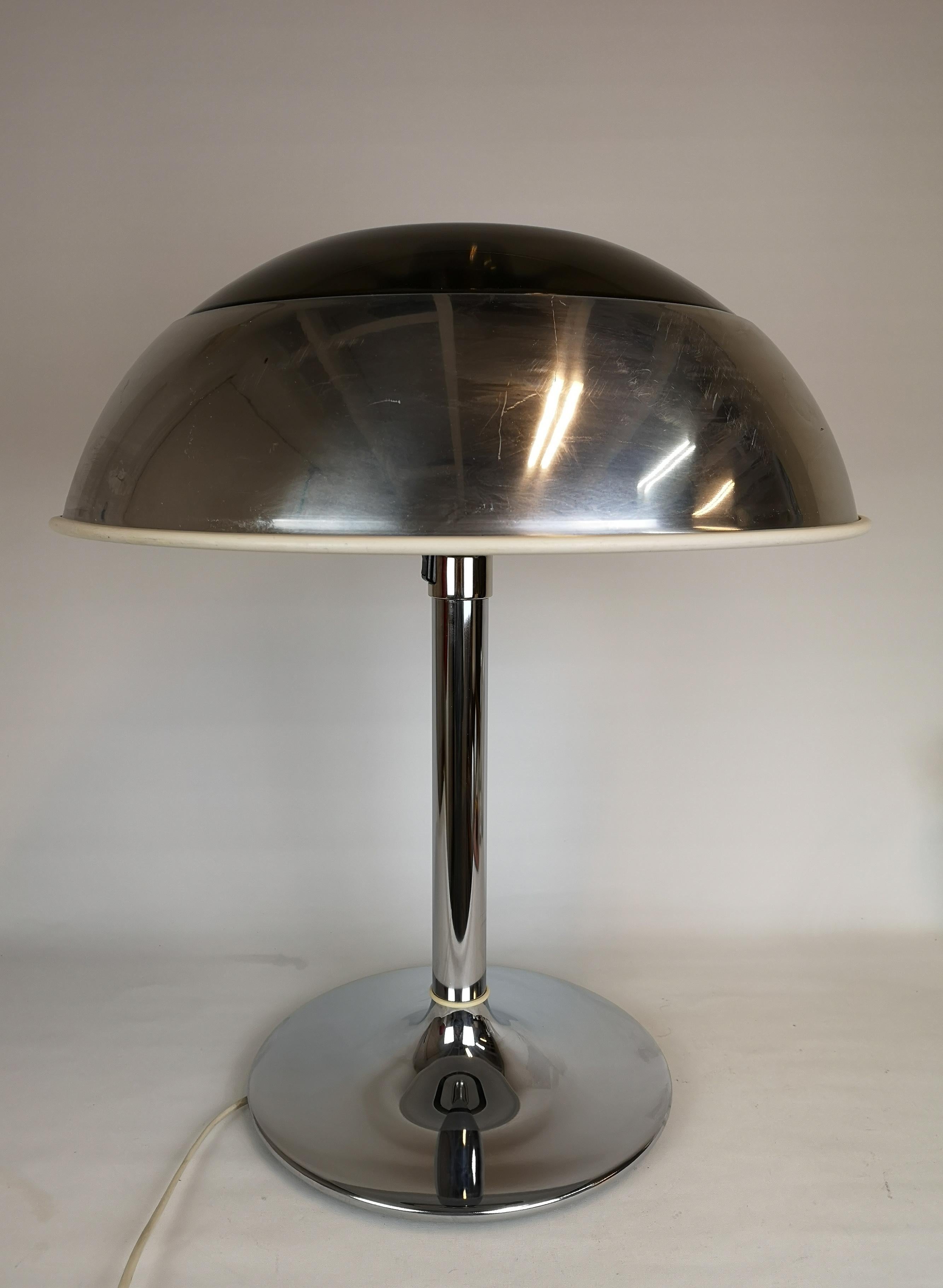 This large chromed table lamp was manufactured at Fagerhults Belysning in Sweden, 1970s.
The shade is in chromed metal and plastic, the rest of it in chromed metal. When lit it gives a nice cool light. 

Good fair working condition, scratches on