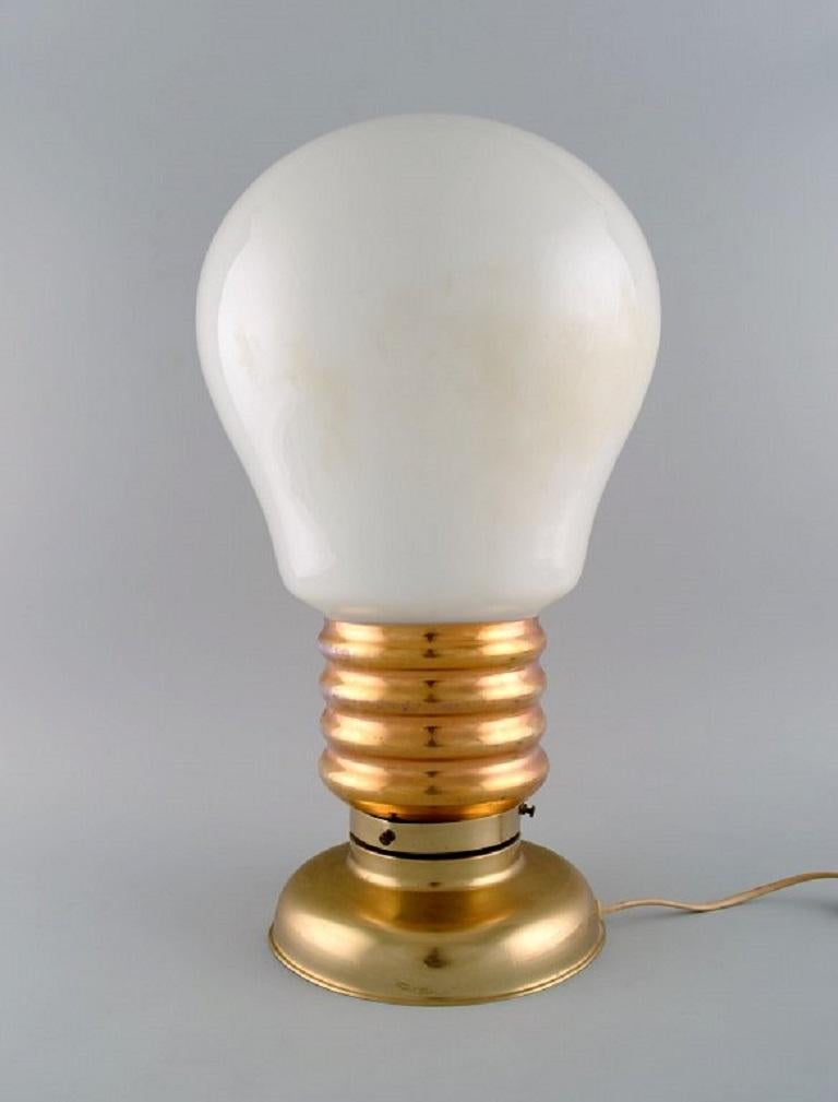 Large table lamp in brass and opal glass shaped like a light bulb. 
1960s.
Measures: 49 x 27 cm.
In excellent condition.