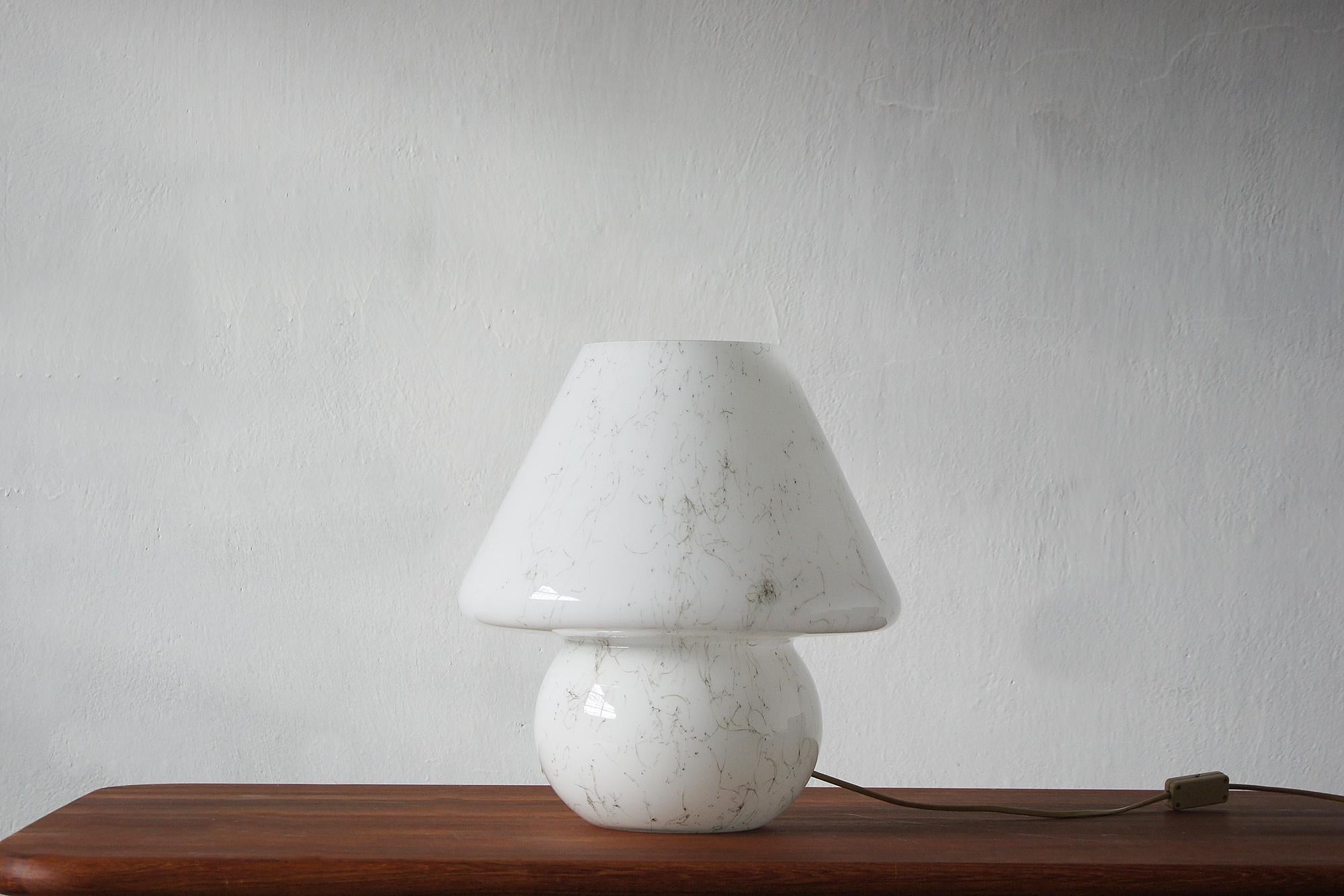 This charming mushroom-shaped table lamp is the essence of Italian design from the 1960s. Its harmonious form—a rounded shade that flows smoothly into the base—is made of white opaline glass with a unique effect of delicate threads characteristic of