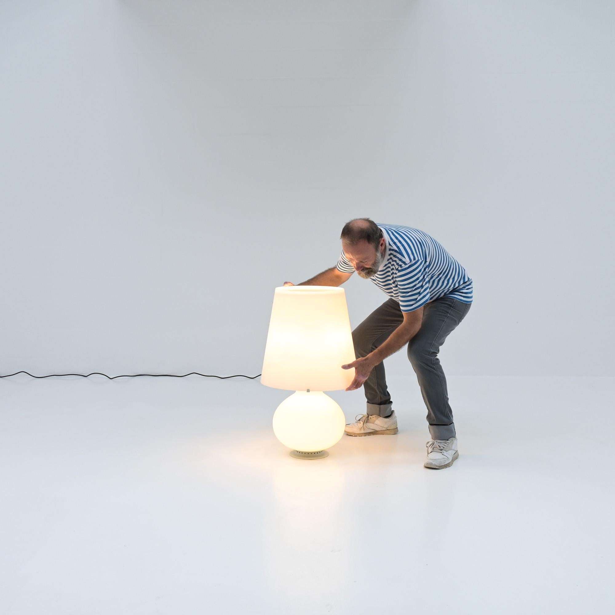 Questa grande lampada da tavolo o da terra, modello 1853/1, è stata disegnata da Max Ingrand nel 1954 per Fontana Arte.
Questa favolosa lampada è realizzata in vetro soffiato bianco smerigliato.  La lampada ha un triplo interruttore per illuminare